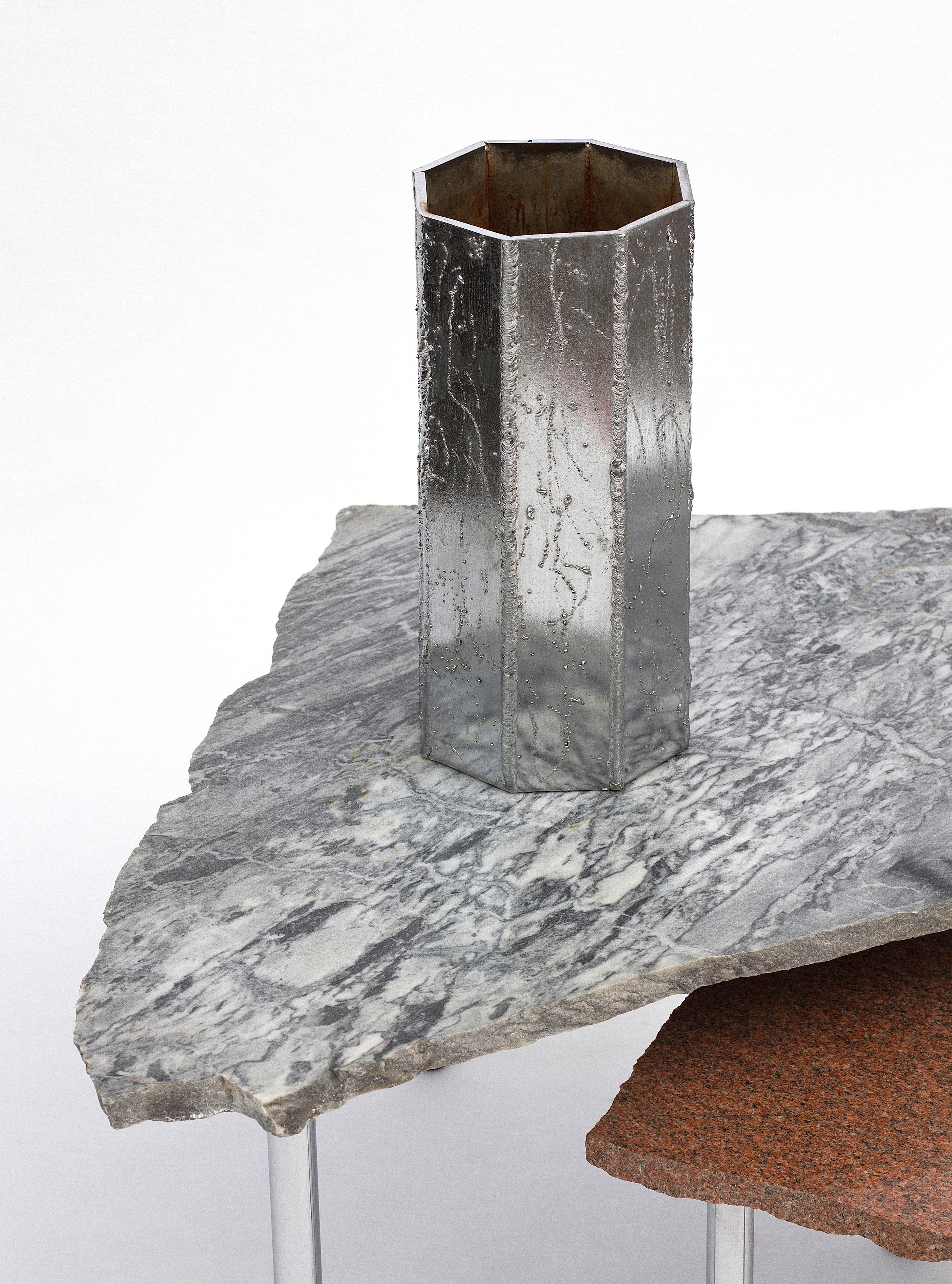 Fabriqué à partir d'acier soudé et chromé, ce vase combine un matériau commun avec une technique brute et une finition intentionnellement grossière pour produire un objet fonctionnel raffiné et magnifique. Chaque lourde plaque métallique est