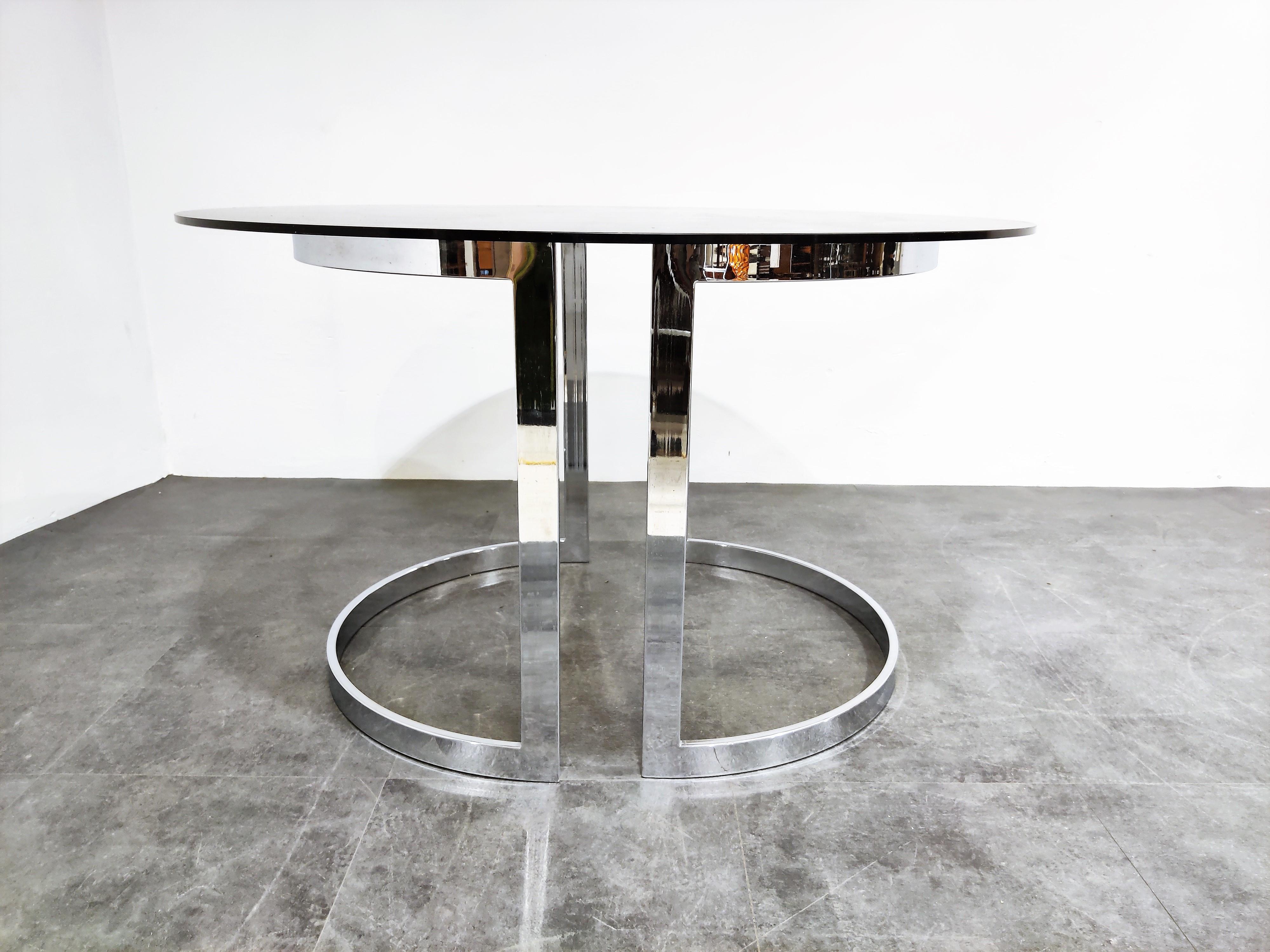 Beautiful Minimalist chromed steel dining table with a round smoked glass top.

The bases can be placed in various ways.

Good condition, small chip on the glass

Charming, timeless piece for in the kitchen or dining room,

1970s,