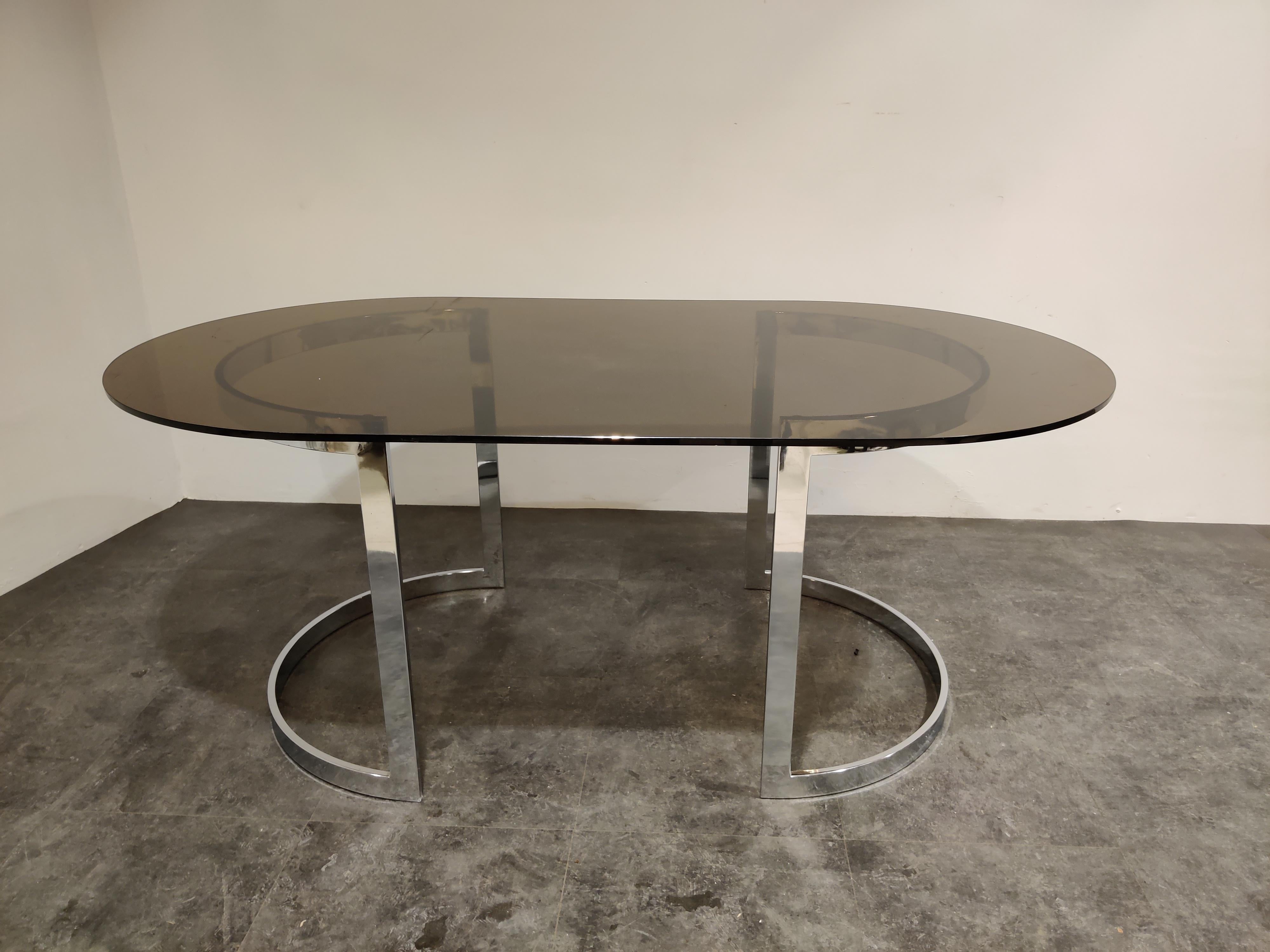 Beautiful Minimalist chromed steel dining table with an oval smoked glass top.

The bases can be placed in various ways.

Charming, timeless piece for in the kitchen or dining room.

1970s - France

Good condition
 
Measures: Height: