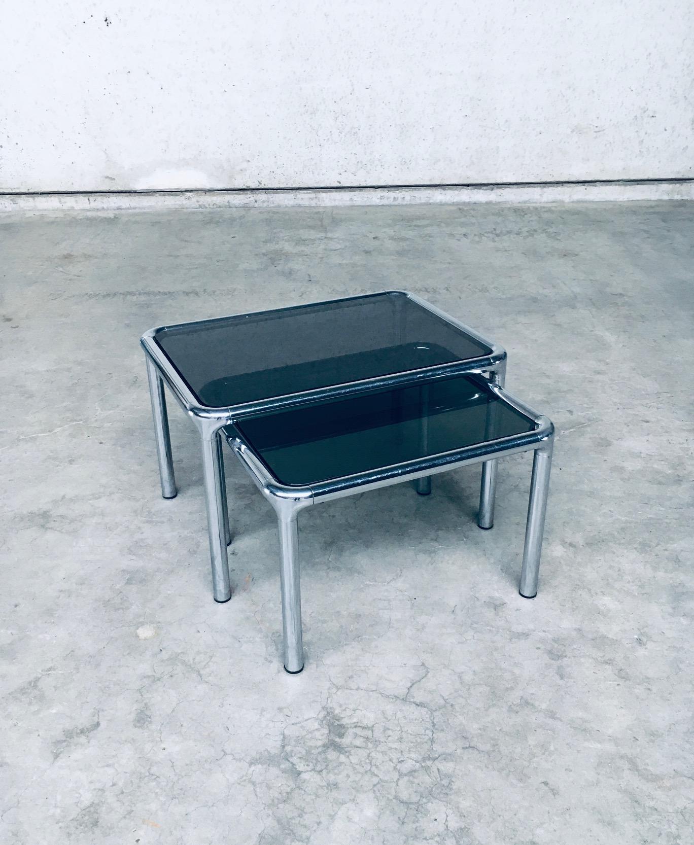 Vintage Midcentury Modern French Design Chrome Steel & Smoked Glass Nesting Table set of 2. Entworfen von Etienne Fermigier. Hergestellt in Frankreich, 1970er Jahre. Dies ist ein sehr schönes und gut gestaltetes Set. Beide Tische sind in sehr gutem
