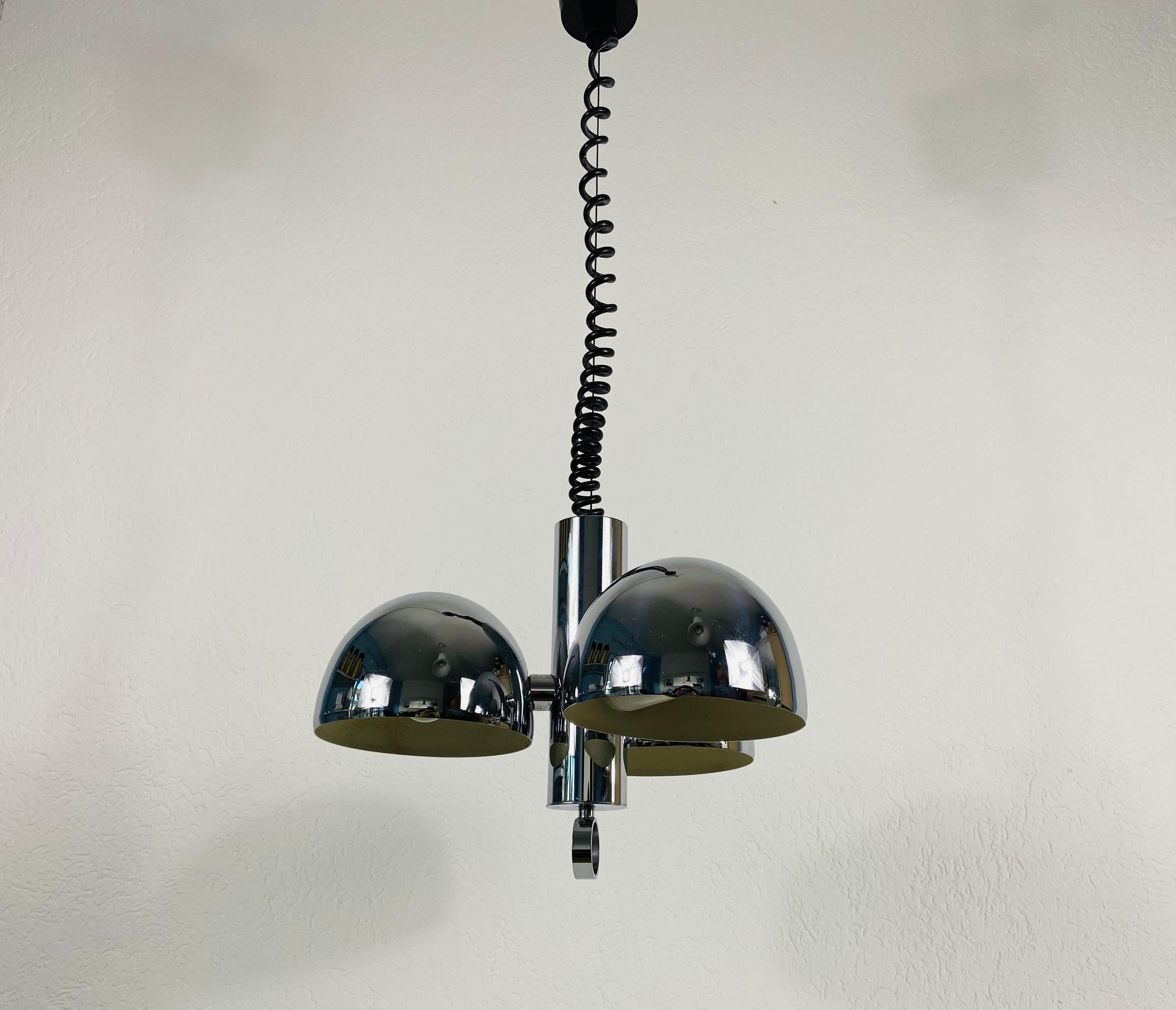 A midcentury chandelier made in the 1960s. It is fascinating with its Space Age design and 3 arms. The chrome circular body of the light is made of full aluminium, including the arms.

Measures: Max height 100 cm
Height of fixture 34 cm
Diameter