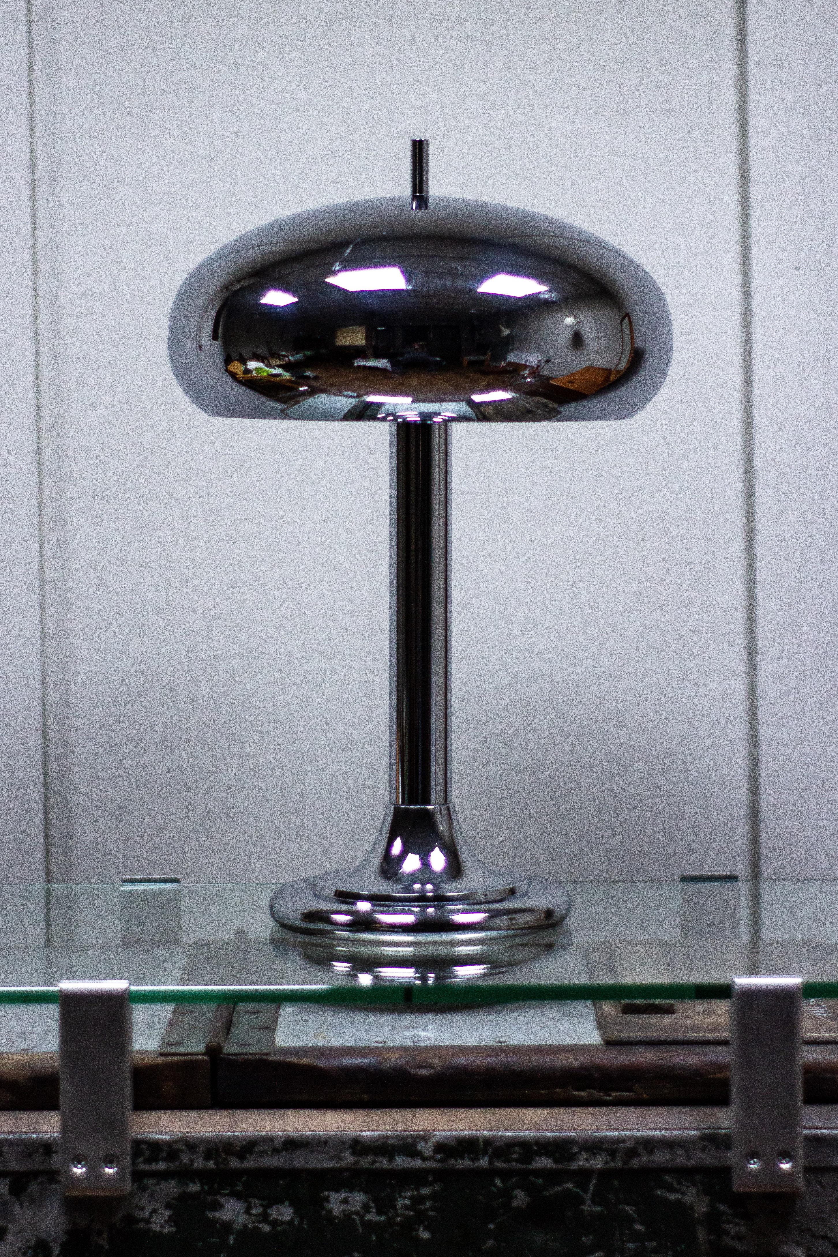 Mid-Century Modern lamp in chrome dates from the 1970s.

Maker and designer unknown. 

Measures: Height 48cm
Width 19cm
Depth 19cm.

Shade measures:
Height 15cm
Width 32cm
Depth 32cm.