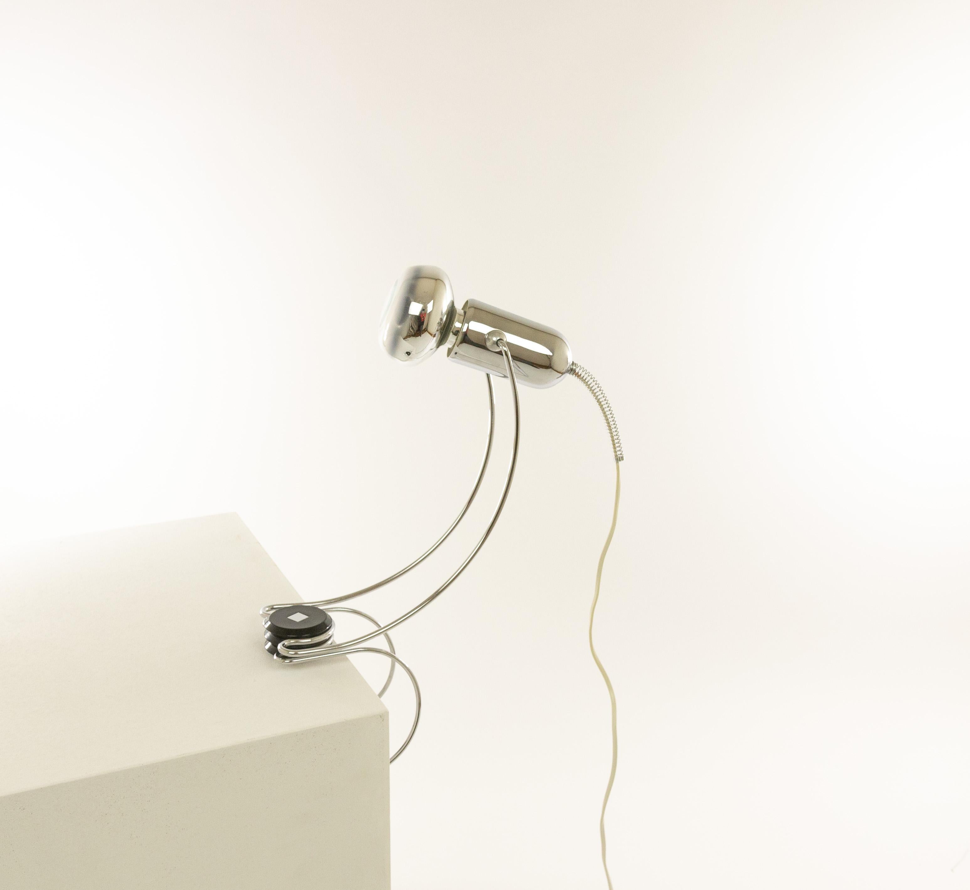 Lámpara de mesa cromada regulable diseñada por Francesco Fois y fabricada por Reggiani durante la década de 1960.

La lámpara, de elegantes formas redondeadas, puede sujetarse con su parte inferior, por ejemplo, a un tablero de mesa. La luz