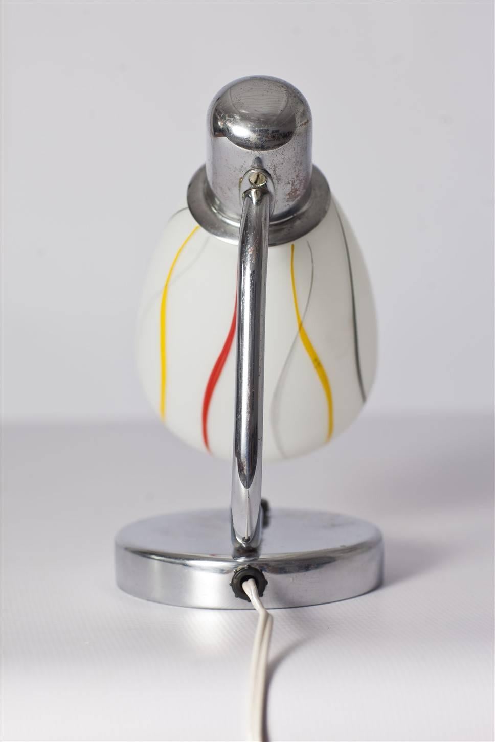 This chrome table lamp was made circa 1940s-1950s by Napako, in former Czechoslovakia. 
Features original lampshade with colorful stripes. Lamp is functional, kept in original, good condition with patina.
Using lightbulbs with an E27 thread.
