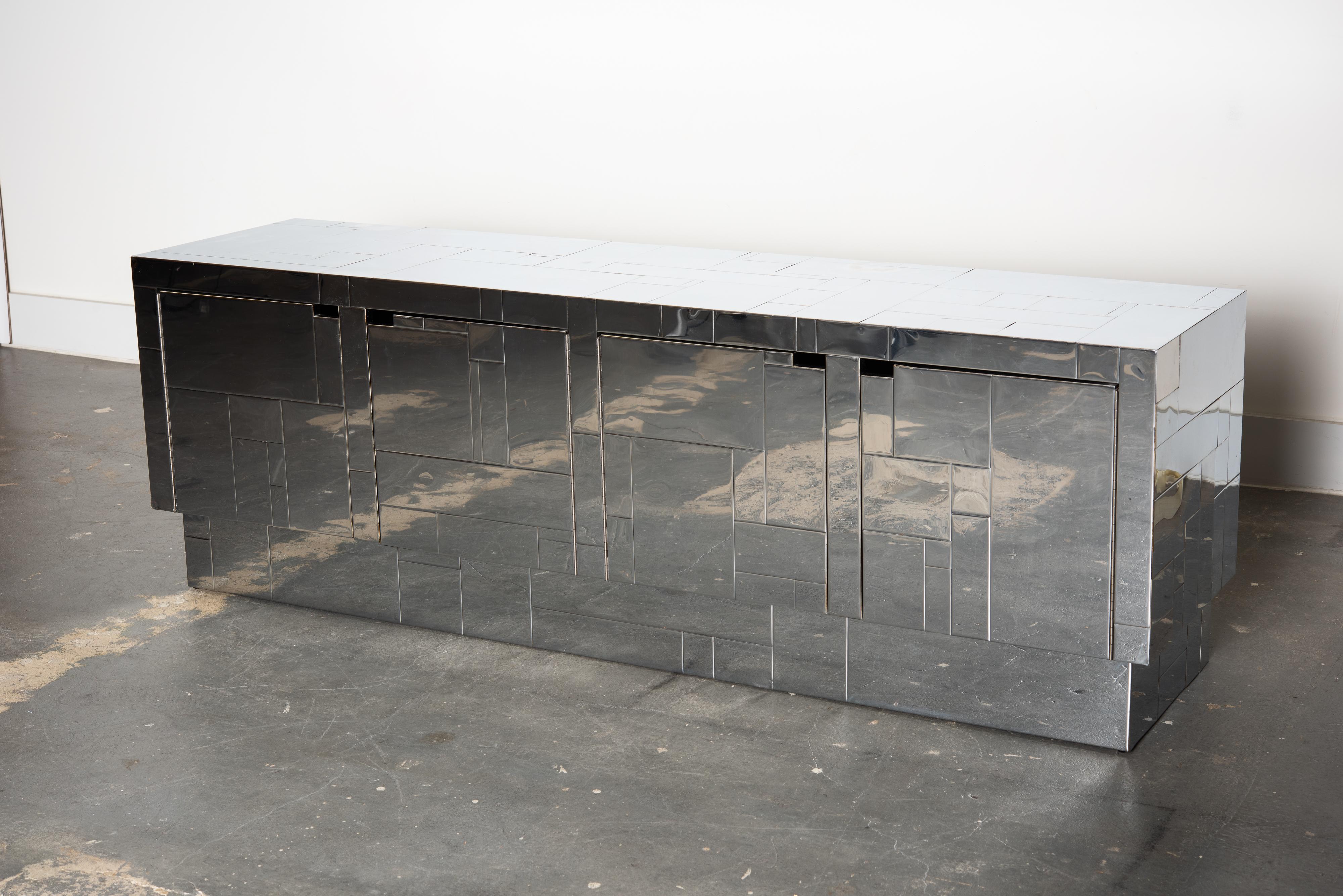 This rare 1970s 'Cityscape' style credenza is after the designs by Paul Evans produced by Directional Furniture. Featuring four doors with blacked out interior space for storage wrapped in chrome tiles in geometric patterns. Works best as a