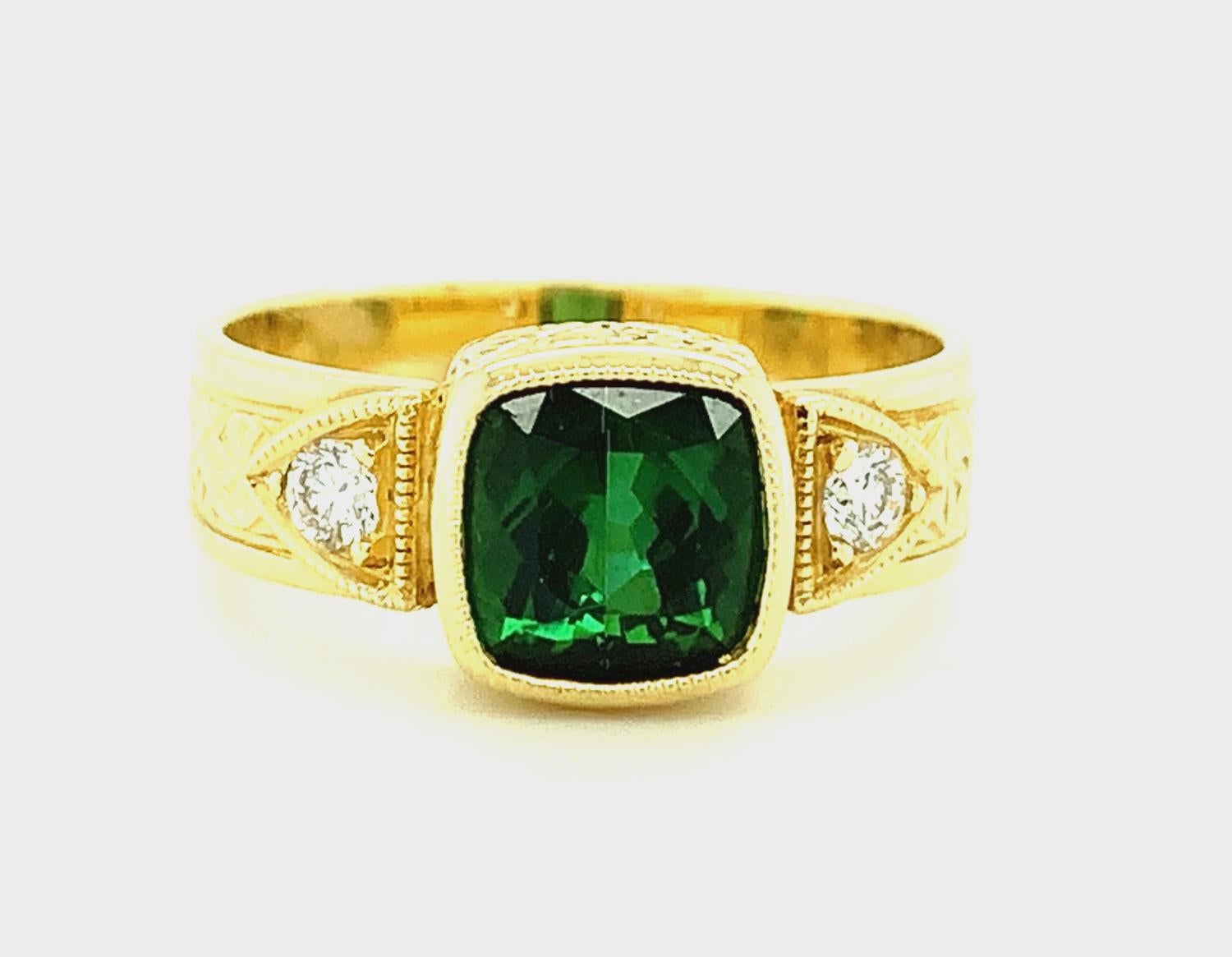 This beautiful ring features a richly colored, 1.58 carat chrome green tourmaline that has been set in a handmade 18k yellow gold bezel. The cushion-shaped gemstone has striking deep, emerald green color and is accented by two sparkling, round