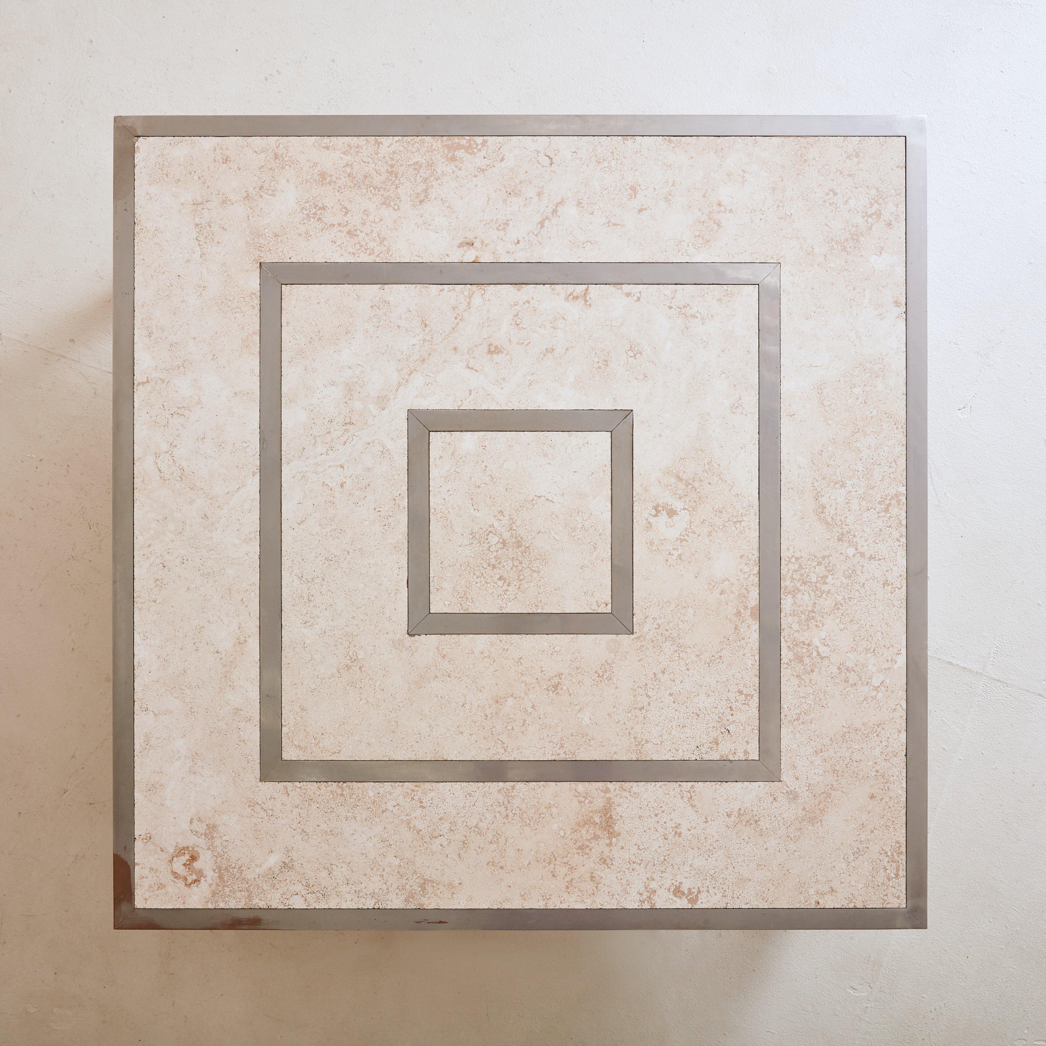 A stunning 1970s Modernist coffee table sourced in the South of France. The square tabletop, crafted from travertine stone in soft beige and taupe hues, features concentric square patterns inlaid with chrome – creating a striking visual contrast