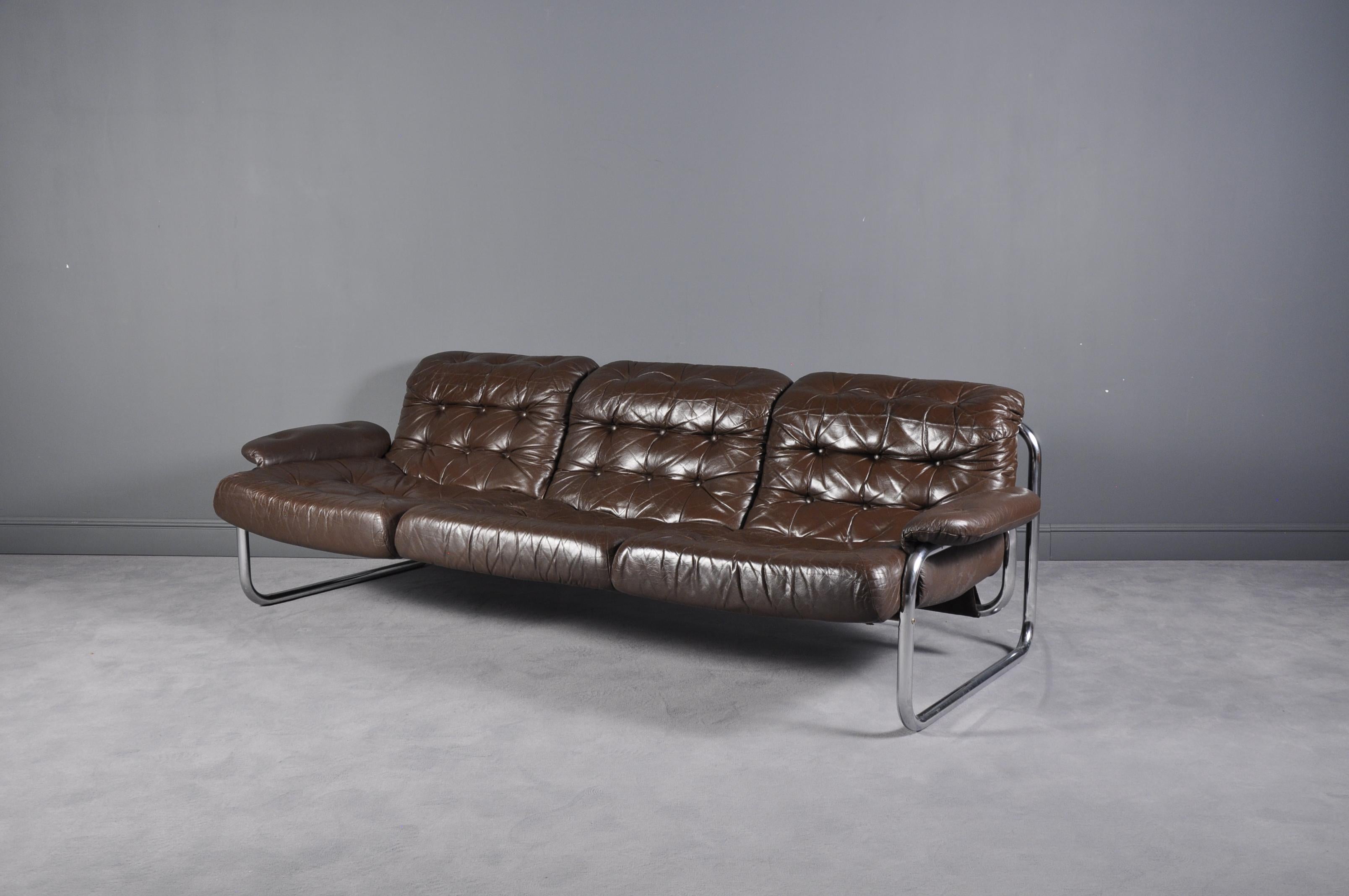 Swedish, 1970s tubular metal framed lounge sofa with original brown tufted cushion and armrests. Produced by Ikea, model Troligen, designed by Johan Bertil Häggström.