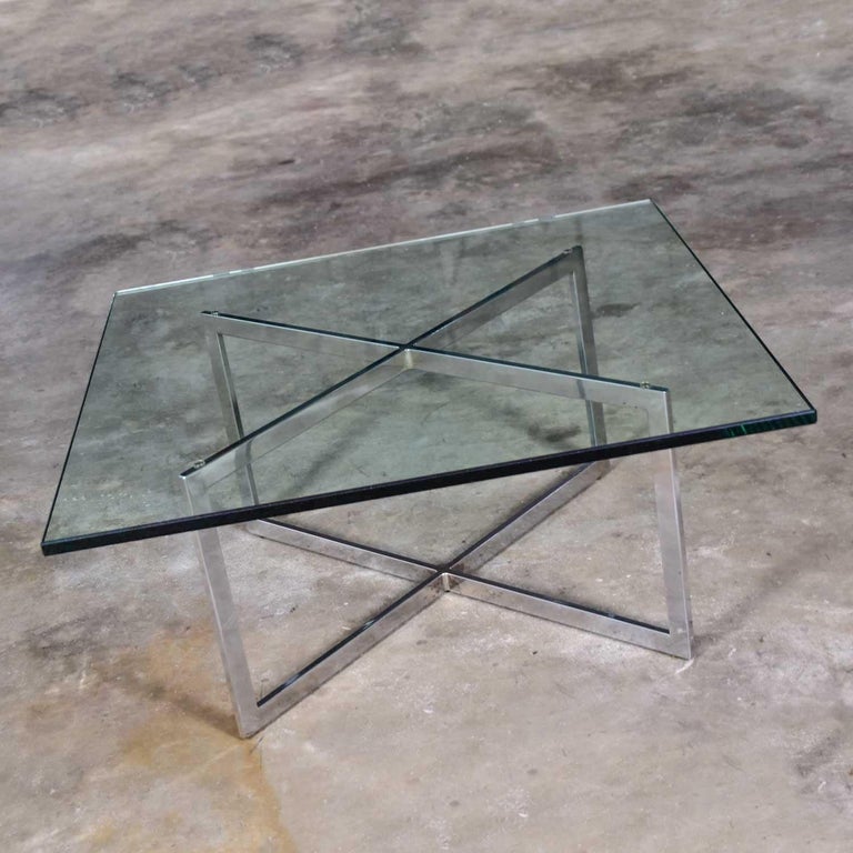 Fabulous square coffee table with a chrome X-base and 3/4-inch-thick glass top in the style of Milo Baughman. Gorgeous vintage condition with minimal wear on the glass. Nothing outstanding that we have detected. Please see photos, circa,