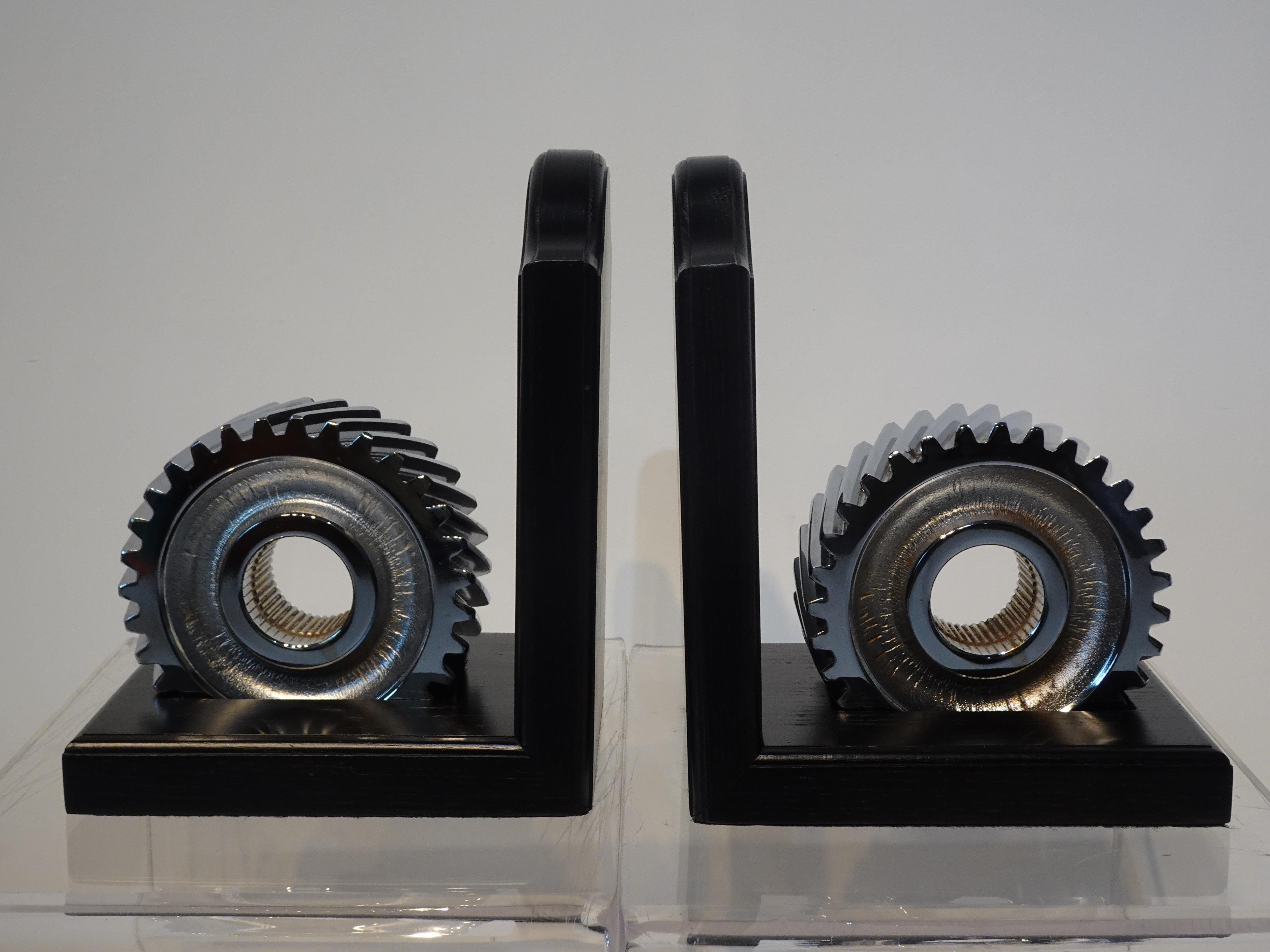 A pair of chrome plated industrial gear bookends free set into cut out slots in the base of the wooden holders which are finished in satin black. Very heavy and can hold many of the larger coffee table or weighty books on your shelve and desk,