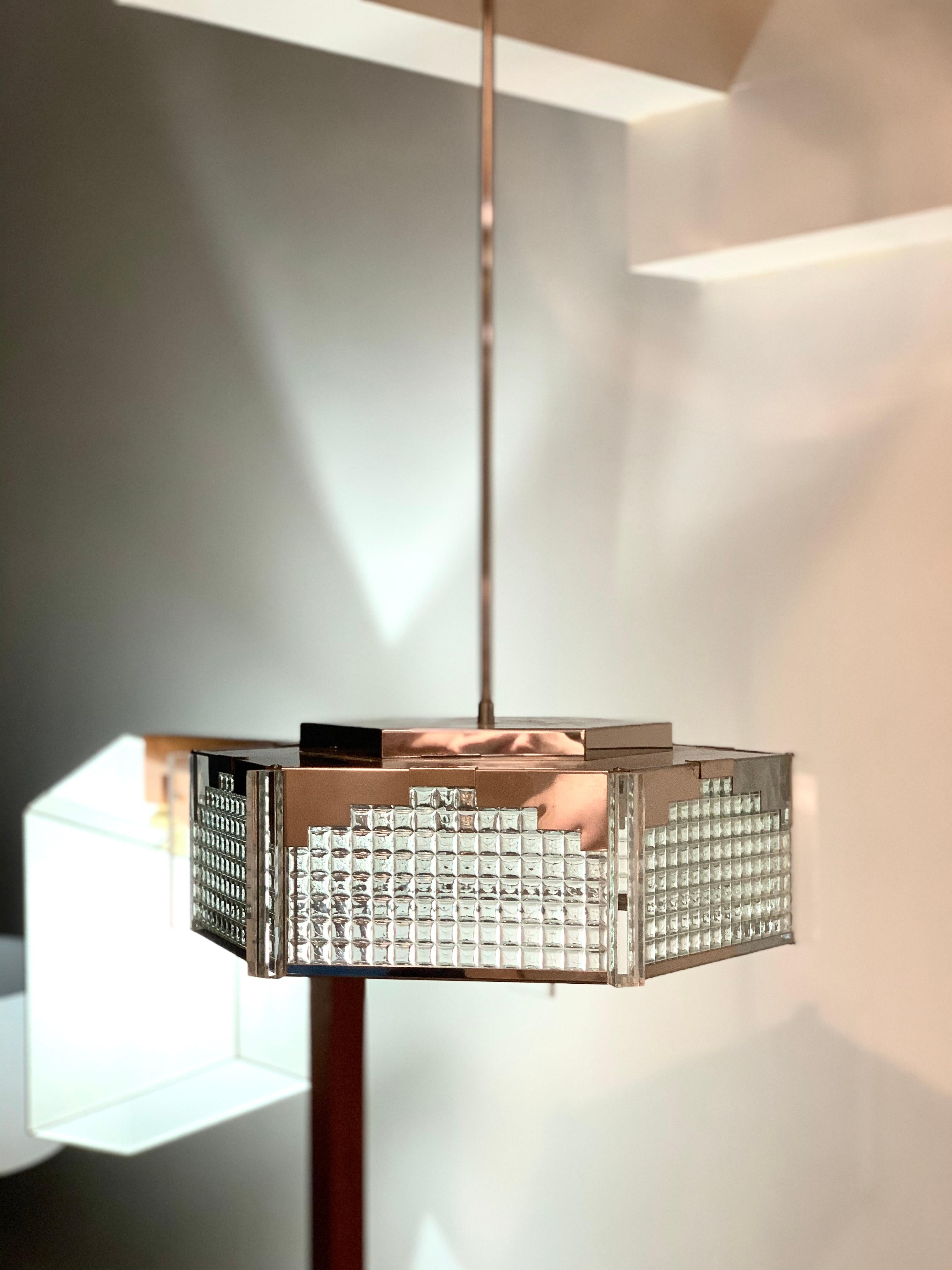 Chromed steel, art glass and Lucite Postmodern pendant fixtureby Fredrick Ramond. Neo-Deco, inspired by the streamline moderne stylings of the 1930s, this Postmodern design incorporates panels of stacked, block glass, a stepped chrome steel frame