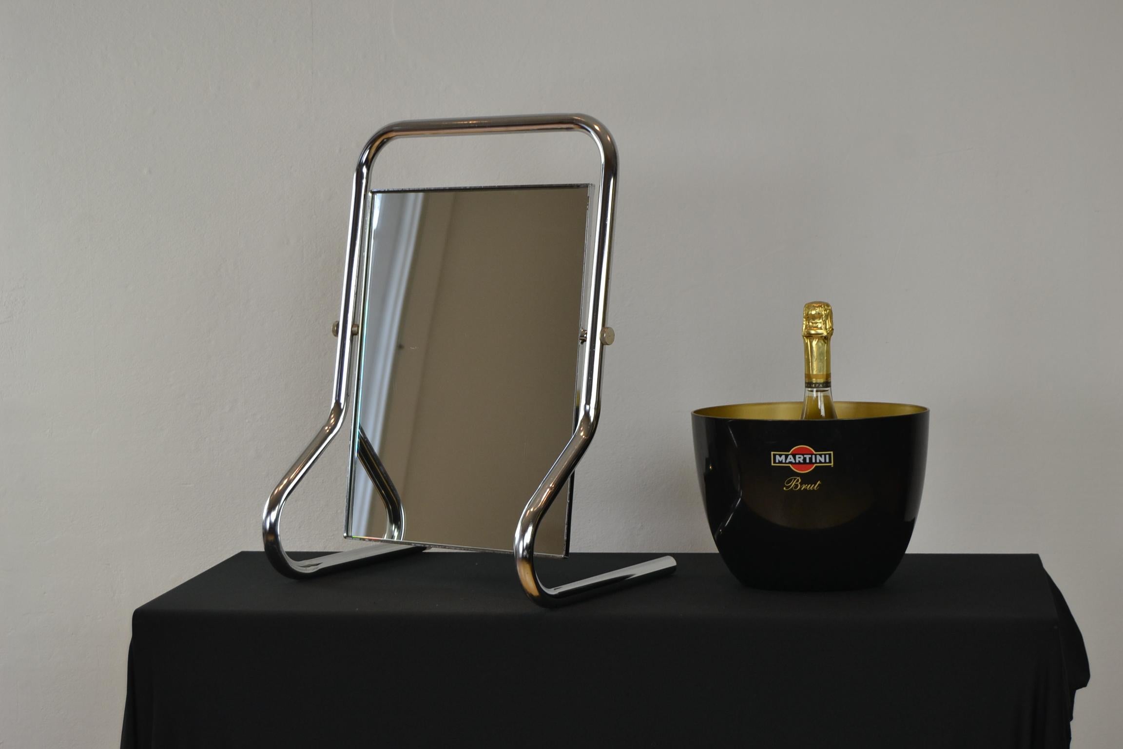 Miroir de table vintage chromé dans le style Bauhaus. 
A  miroir de table avec cadre en tube de métal chromé arrondi. 
La glace rectangulaire de ce miroir de courtoisie peut être placée dans la position que vous souhaitez grâce aux deux boulons