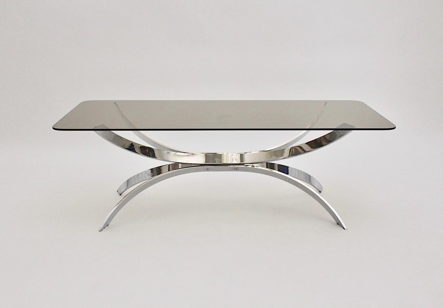 Chromed metal sculptural vintage coffee table or sofa table with rectangular smoked glass top designed and manufactured 1970s.
The chromed metal base shows a beautiful movement and provides a cool and sophisticated touch throughout its silver tone.