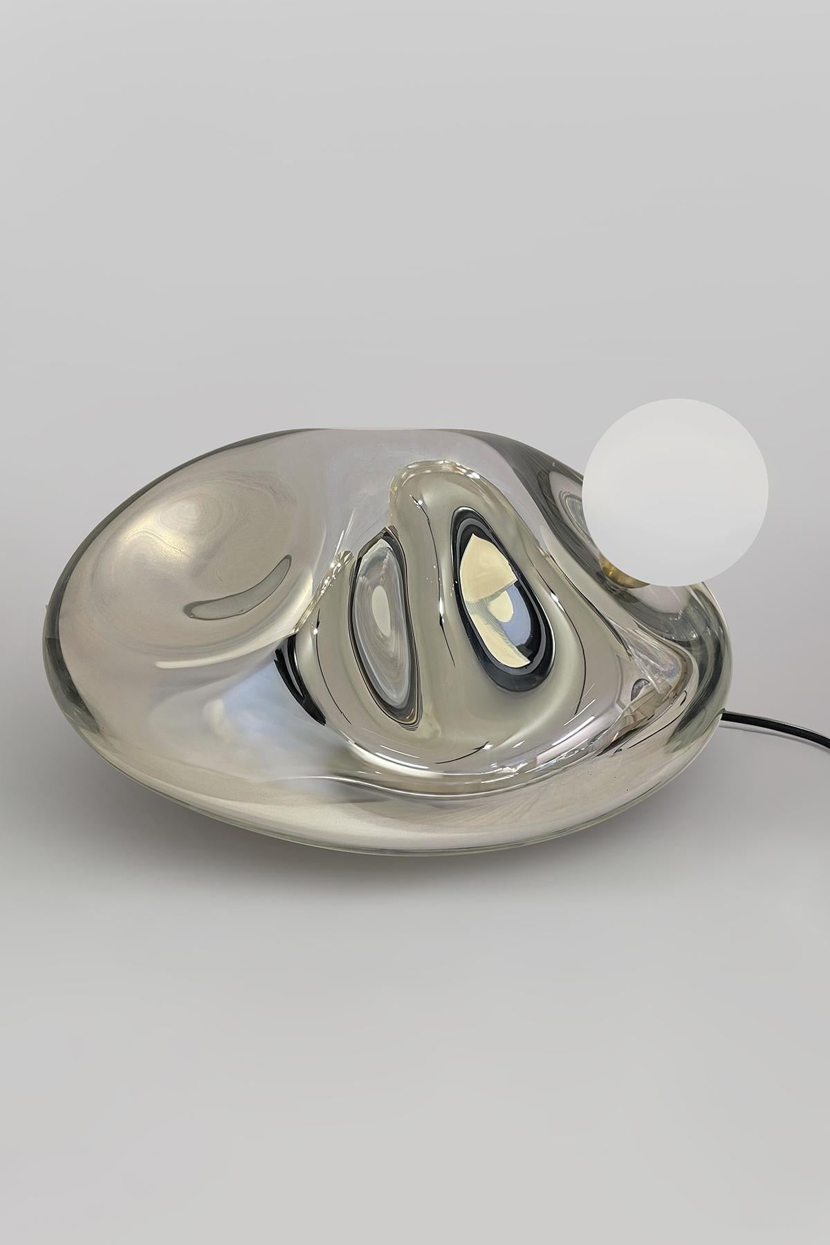 Chromite Lamp II Table Lamp by Homa
Dimensions: W 42 x D 31 x H 40 cm
Materials: Blown Glass. Smoke Mirror.

HOMA is a contemporary design atelier based in Istanbul. The atelier’s trademark processes are handblown glass, glass fusing and mirroring,