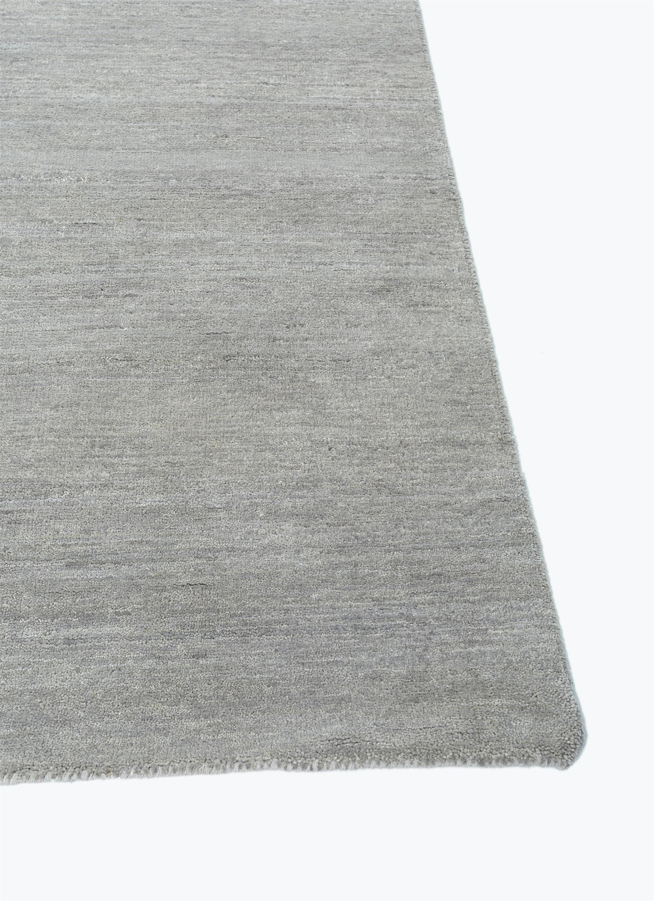 Immerse yourself in the timeless elegance of this hand-knotted rug that paints a canvas of serenity and reflection. The ashwood ground and honey border evoke a palette of nature's tranquility. This modern masterpiece invites a moment of pause, a