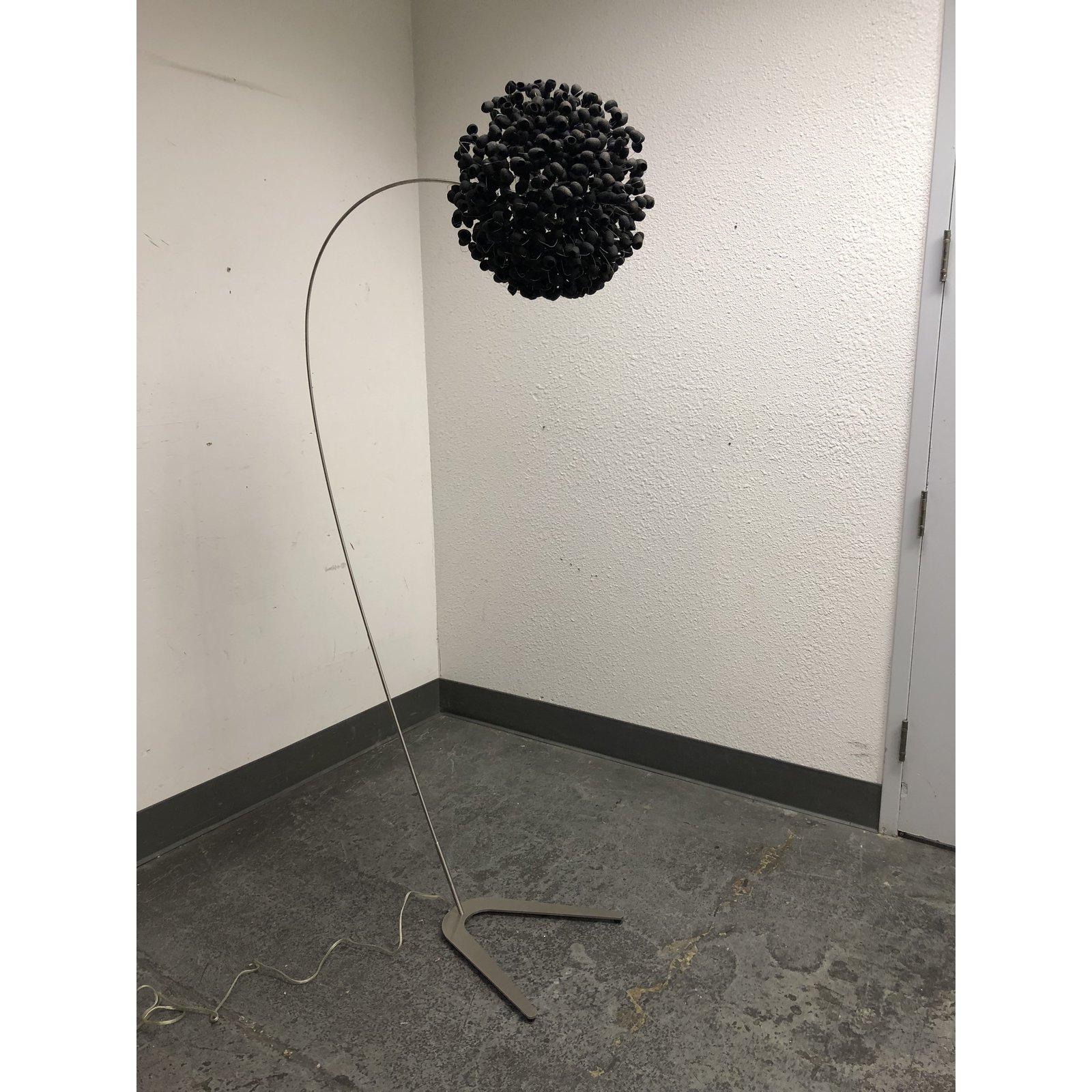 A Chrysalis Sky black floor lamp by Ango. This stunning floor lamp evocative of a dandelion in bloom, will bring a striking and enchanting look to any room in your home. The stainless steel metal base is slightly curved with a globe shaped shade