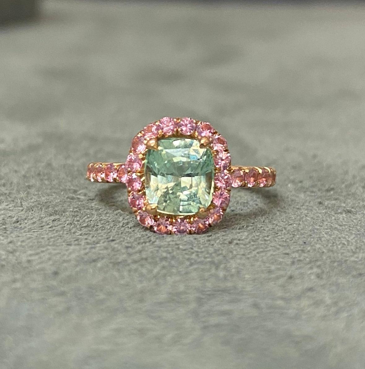 A beautiful chrysoberyl with an unusual pastel green colour set with light pink sapphires in 18k rose gold. The pink sapphires are set approximately 2/3 of the way around the band. The ring is hand-made in Geneva, and is a perfect fit for the little