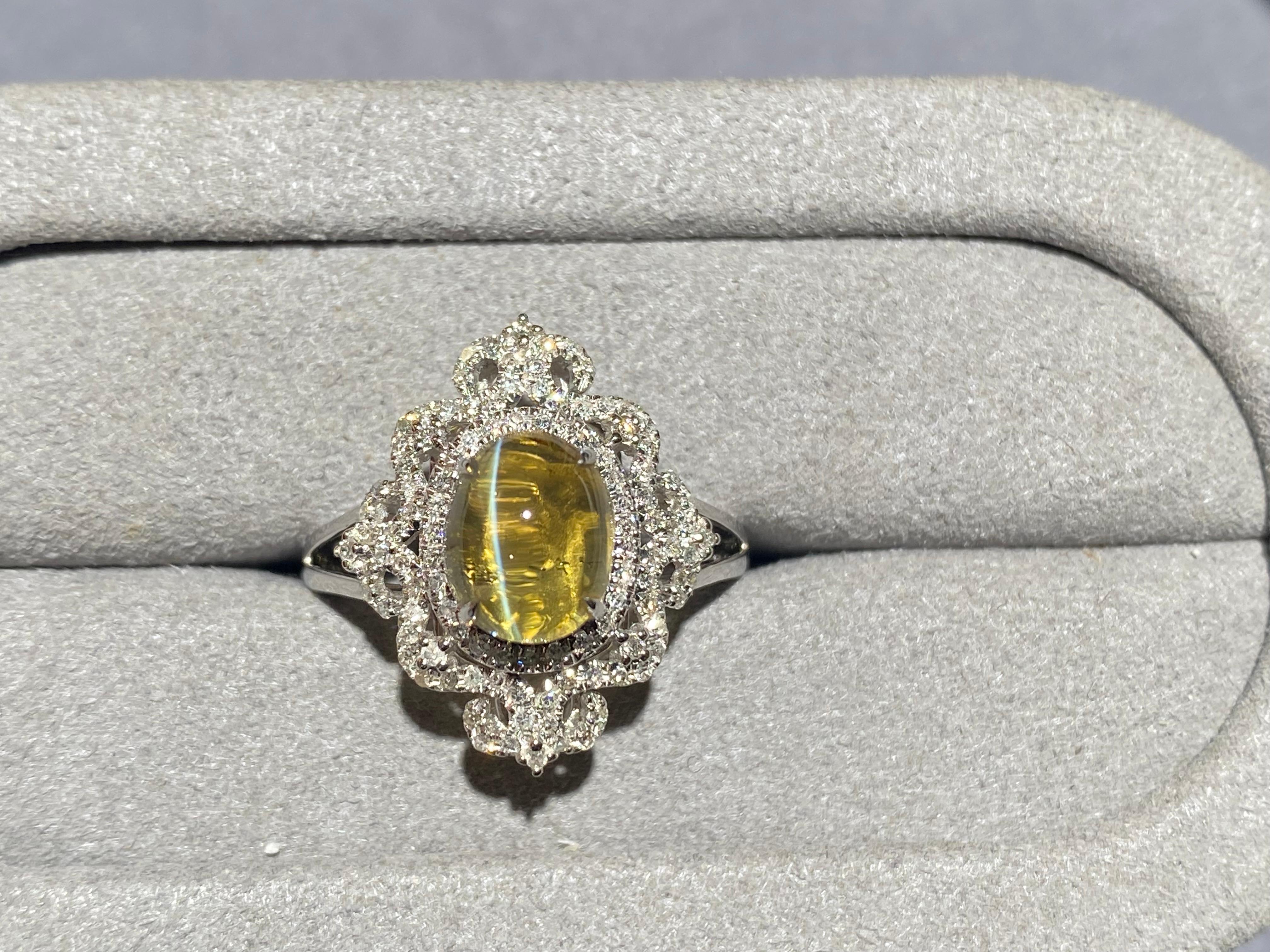 A Chrysoberyl cat's eye and diamond ring in 18k white gold. This is a classical design with the main stone surrounded by repetitive pattern set with diamond pave. 

US Ring size 7.5
Total diamond weight is 0.618 ct 