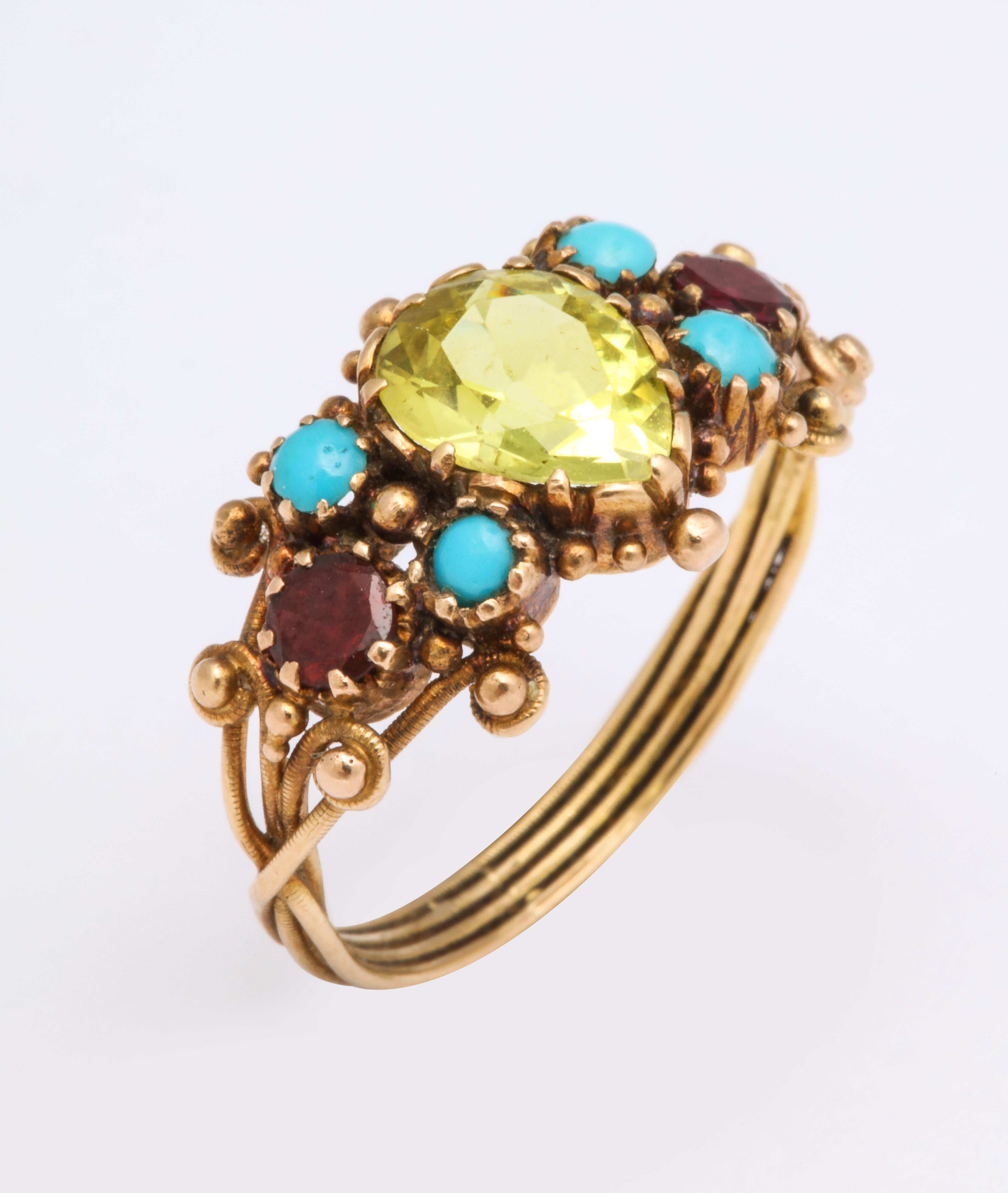 Made circa 1820, this lovely English ring is set with a central chrysoberyl surrounded by four turquoise and two oval almandine garnets. All set in 22k gold. 