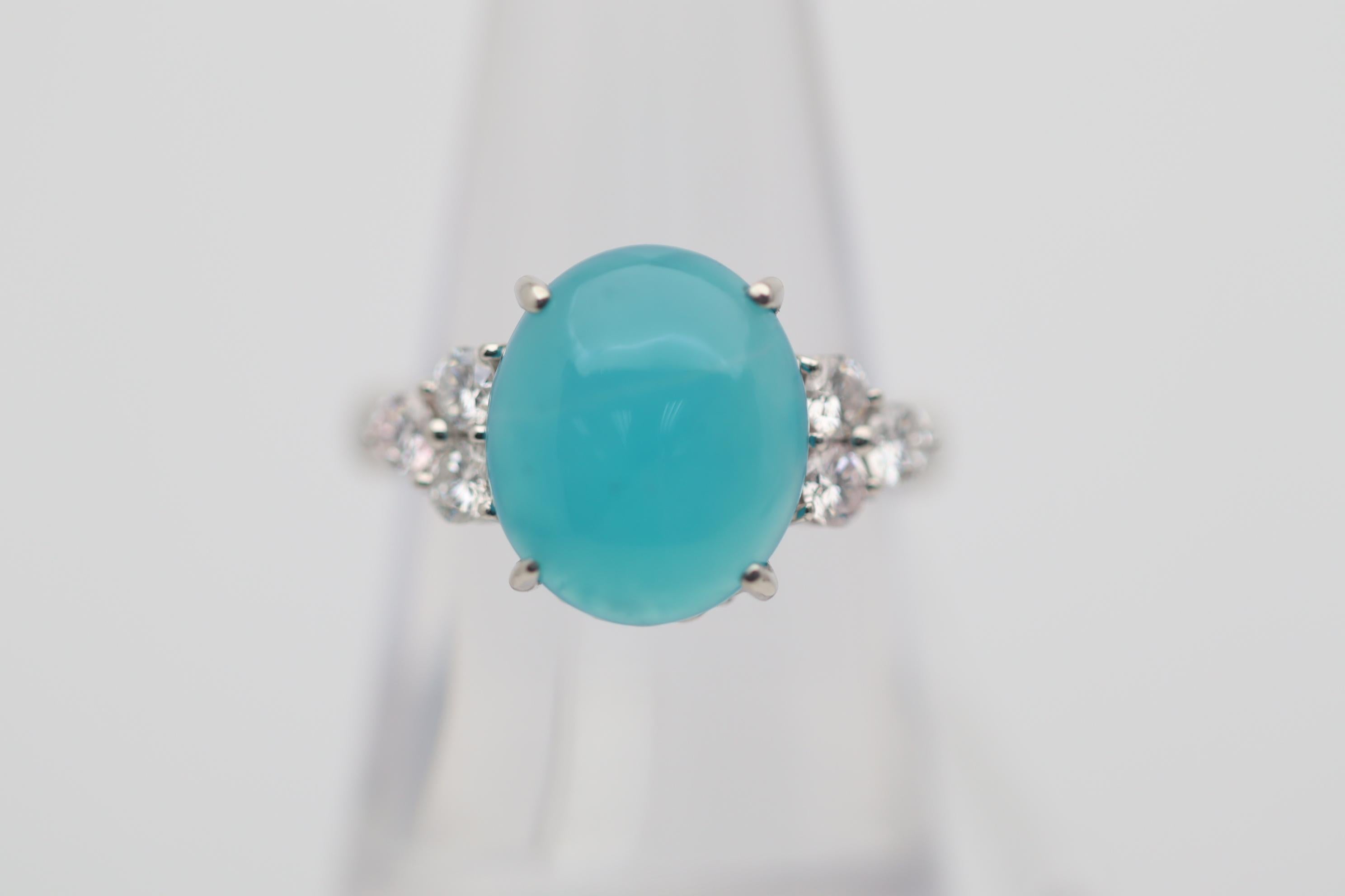 A fine and unique gemstone, chrysocolla, the bright blue variety of chalcedony, takes center stage. It weighs 4.24 carats and has a rich slightly greenish-blue color that is so pleasing to look at. It is complemented by 0.50 carats of round