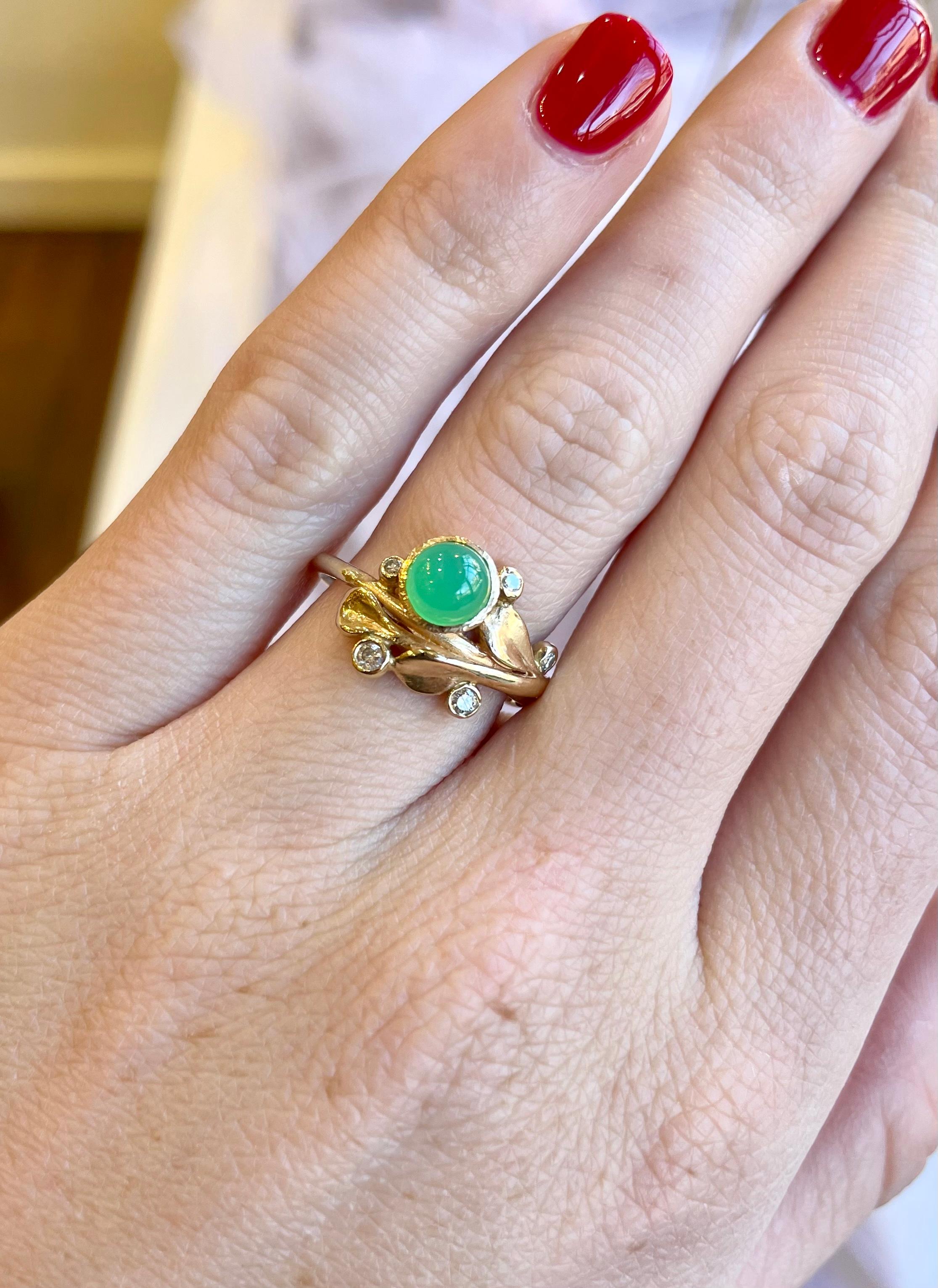 Blütenring aus 14kt Gelbgold mit 4 runden Brillanten und einem 5,5 mm Cabochon aus grünem Chrysopras  Mittelstein. Handgebürstete Details auf goldenen Blütenblattakzenten. 

US Fingergröße 7

Gewicht: 4,07g

Von Petal Nature inspiriertes,