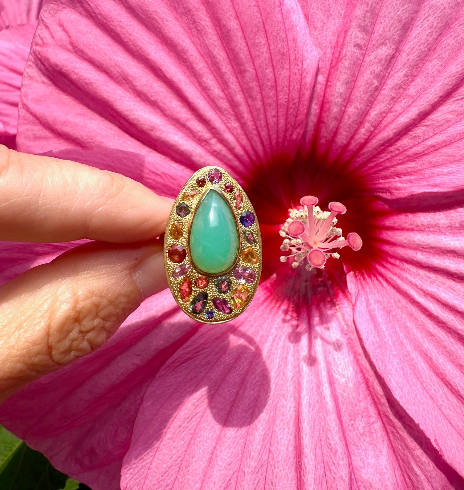 Luminosi zaffiri sfaccettati multicolore circondano una pietra centrale a forma di pera di crisofraso verde brillante, il tutto incastonato in una spettacolare montatura a grani d'oro 18kt.  Disegnato dalla pluripremiata designer di gioielli Lauren