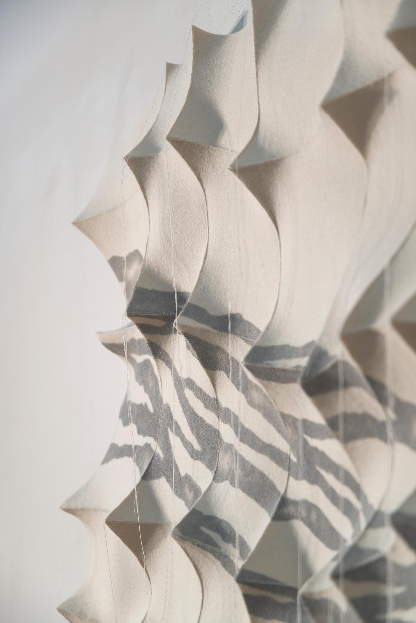This contemporary tapestry, inspired by nature, is white with patterns in gray.

The uniquely stunning sculptural fibre art of Chung-Im Kim has garnered her international recognition. Inspired by her own rich Korean heritage and intricate patterns