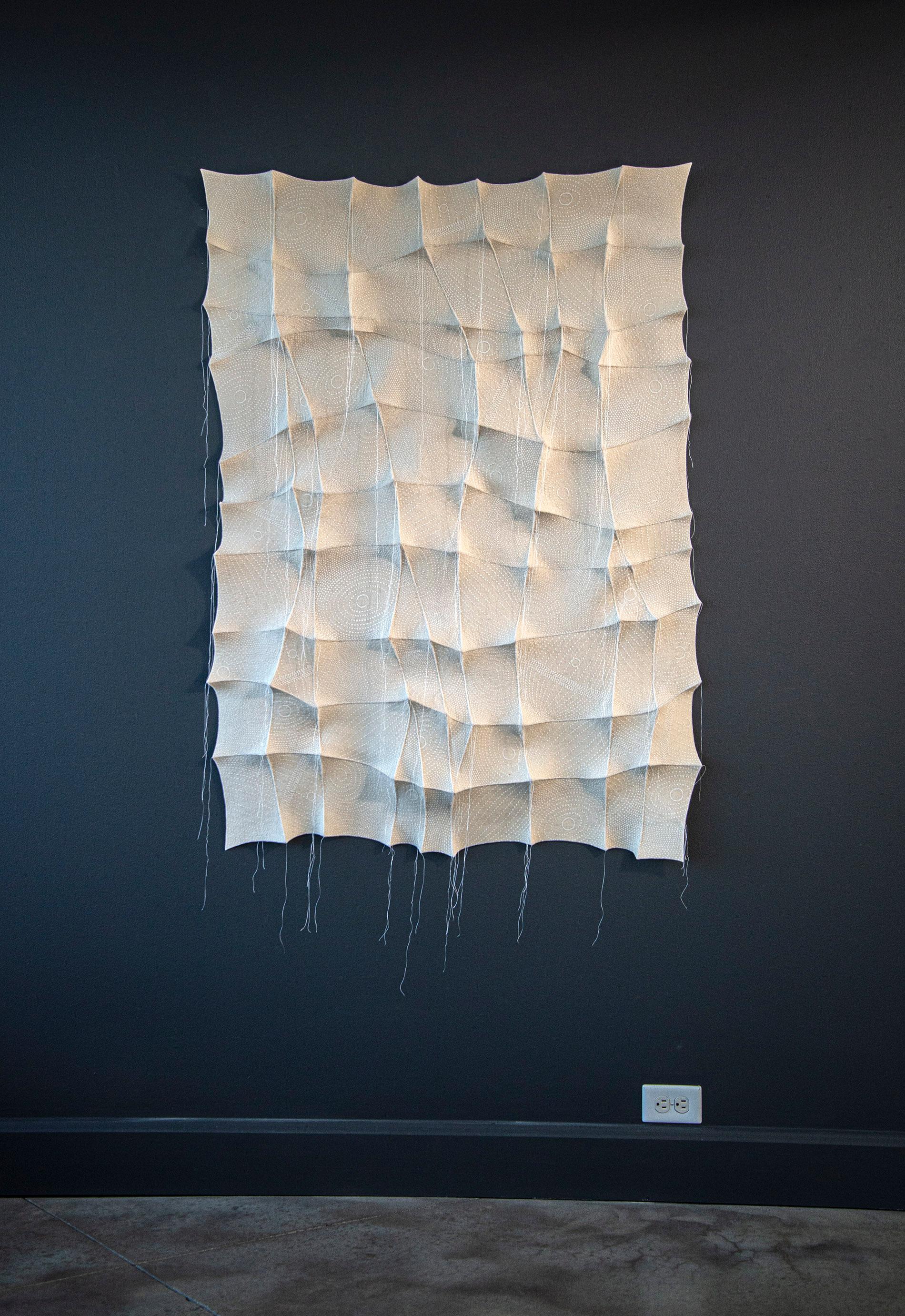 In this elegant monochromatic white tapestry by fabric artist Chung-Im Kim, finely detailed patterns swirl around the fabric. Kim’s organic form is inspired by the patterns she sees in nature. The white ink on white fabric provides a subtle texture.