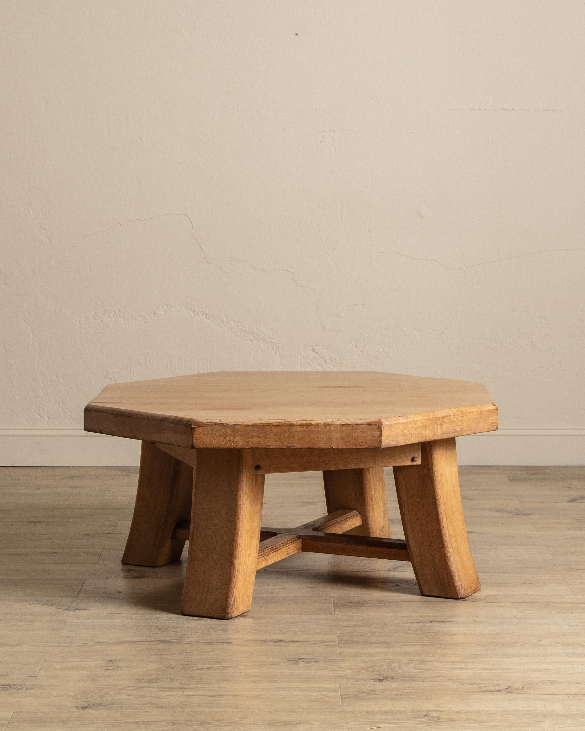 Dieser Couchtisch aus französischer Eiche, der um 1960 hergestellt wurde, ist ein eindrucksvolles Beispiel für brutalistisches Design. Mit seiner kühnen achteckigen Platte und den klobigen, abgewinkelten Beinen strahlt er eine starke
