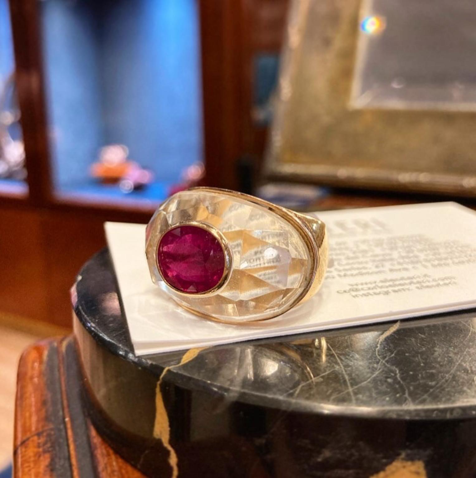 Un audaz anillo de oro amarillo con una prominente cúpula de cristal de roca facetado en la que cuelga un rubí talla oval de 4,82. Alrededor de 1980.