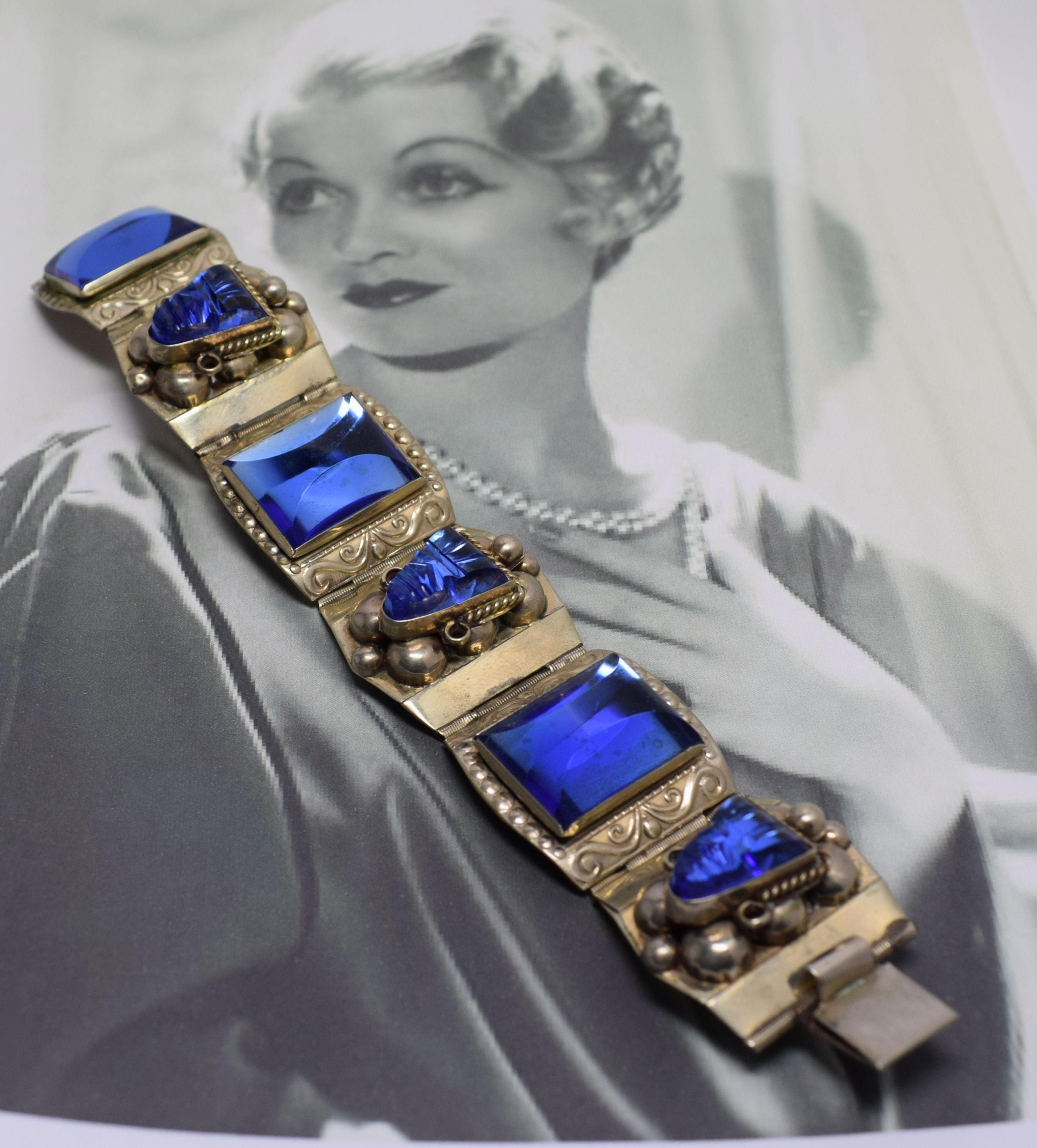 This bracelet is a real gem in more ways than one. Dating to mid century and marked Sterling 925 Taxco, this chunky panel bracelet with beautiful vivid blue Aztec head glass cabochon features 6 deep blue glass raised panels. Each sterling panel has