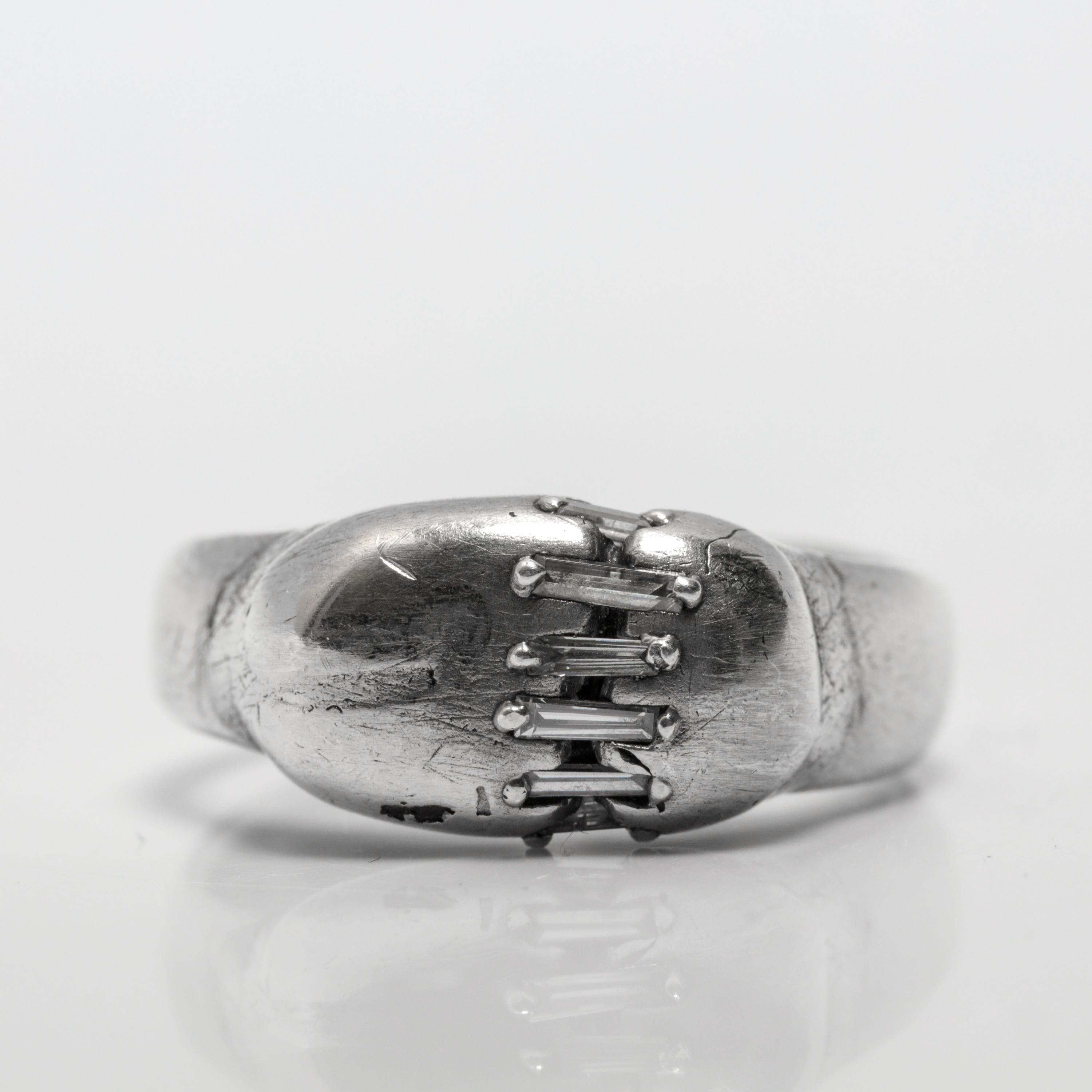 Dieser bemerkenswerte Ring von Atelier Narce aus New York City ist ein Gespräch in Metall - ein beredtes Geflüster von Trotz, Humor und Widerstandsfähigkeit. Dieser einzigartige Ring aus Sterlingsilber, der in den 2020er Jahren gefertigt wurde und