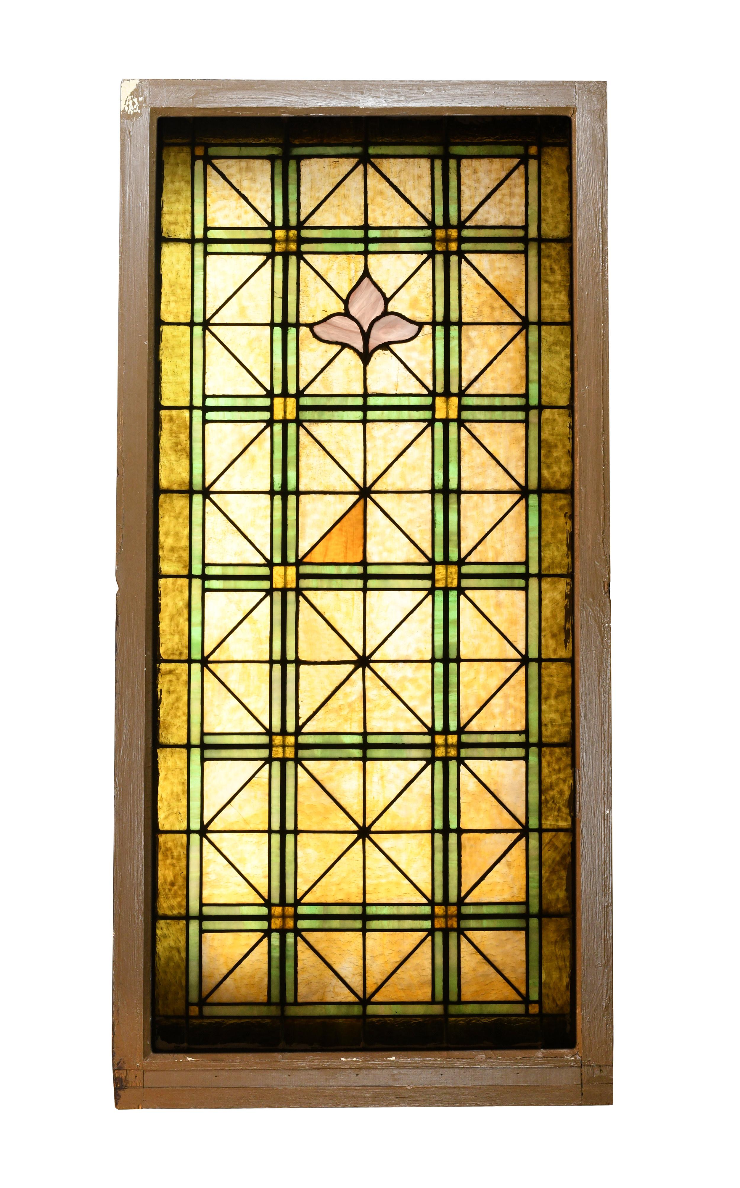 Beautiful stained glass church window divided into neat and tidy triangular shapes. Green glass pieces border heavily textured amber glass throughout, and a stylized purple fleur de lis creates a beautiful focal point near the top of the window.