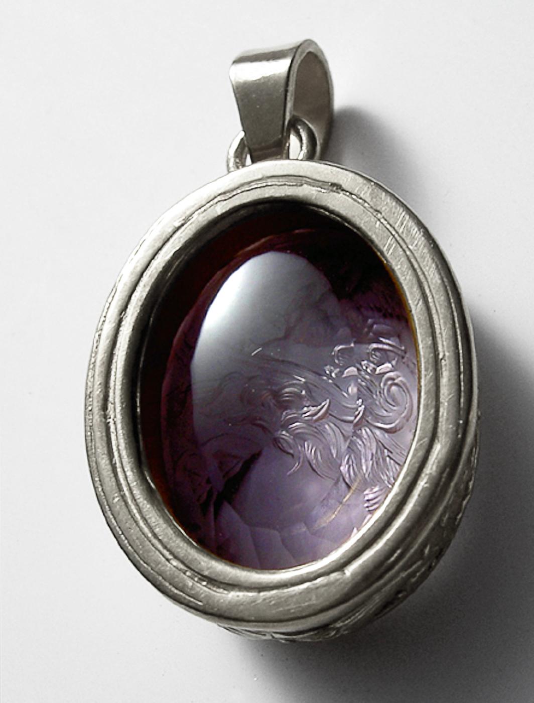 This exquisite intaglio is masterfully engraved onto amethyst and features a depiction of Athena. The stone is set in a 925 sterling silver pendant. 

Athena (Minerva) is the goddess of wisdom, courage, handicraft, and battle. She’s often depicted