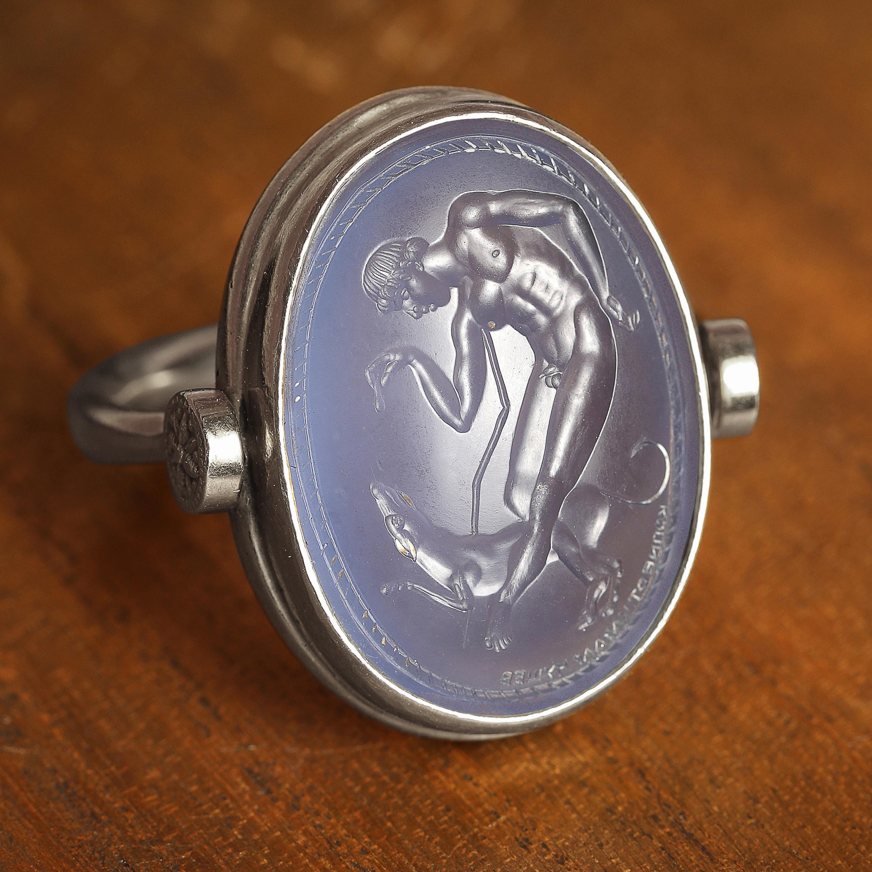 This exquisite intaglio is masterfully engraved onto blue chalcedony gemstone and features a boy with his dog. The stone is set in a 925 sterling silver swivel ring.

Production time for this piece is 4-6 weeks.

Can be made in any size ranging from