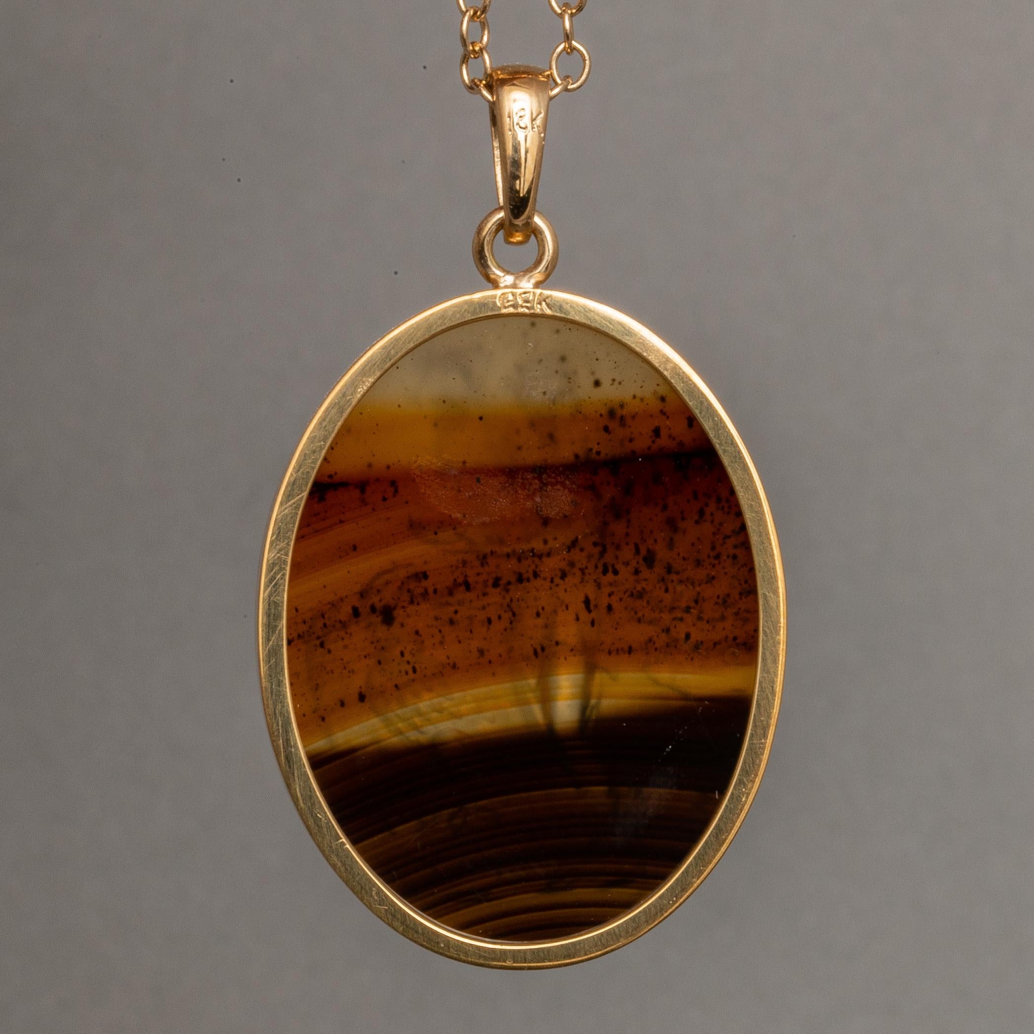 Cette intaille exquise est gravée de main de maître sur un spécimen d'agate du Montana et présente une représentation d'Hébé et de Zeus. La pierre est sertie dans un pendentif en or karat 18K. L'agate du Montana est très prisée pour sa couleur riche