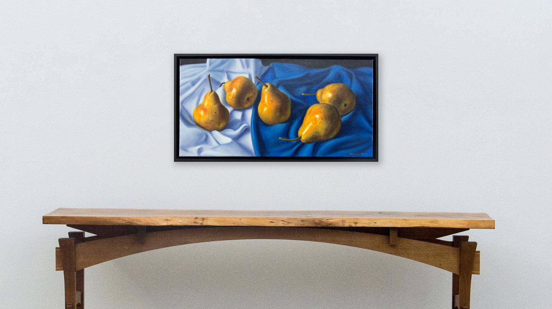 Luscious golden pears are arranged on a blue and white cloth in this realistically rendered and intimate oil painting on canvas by Ciba Karisik. In addition to the skillful use of trompe l'oeil, the artist has heightened the importance of the