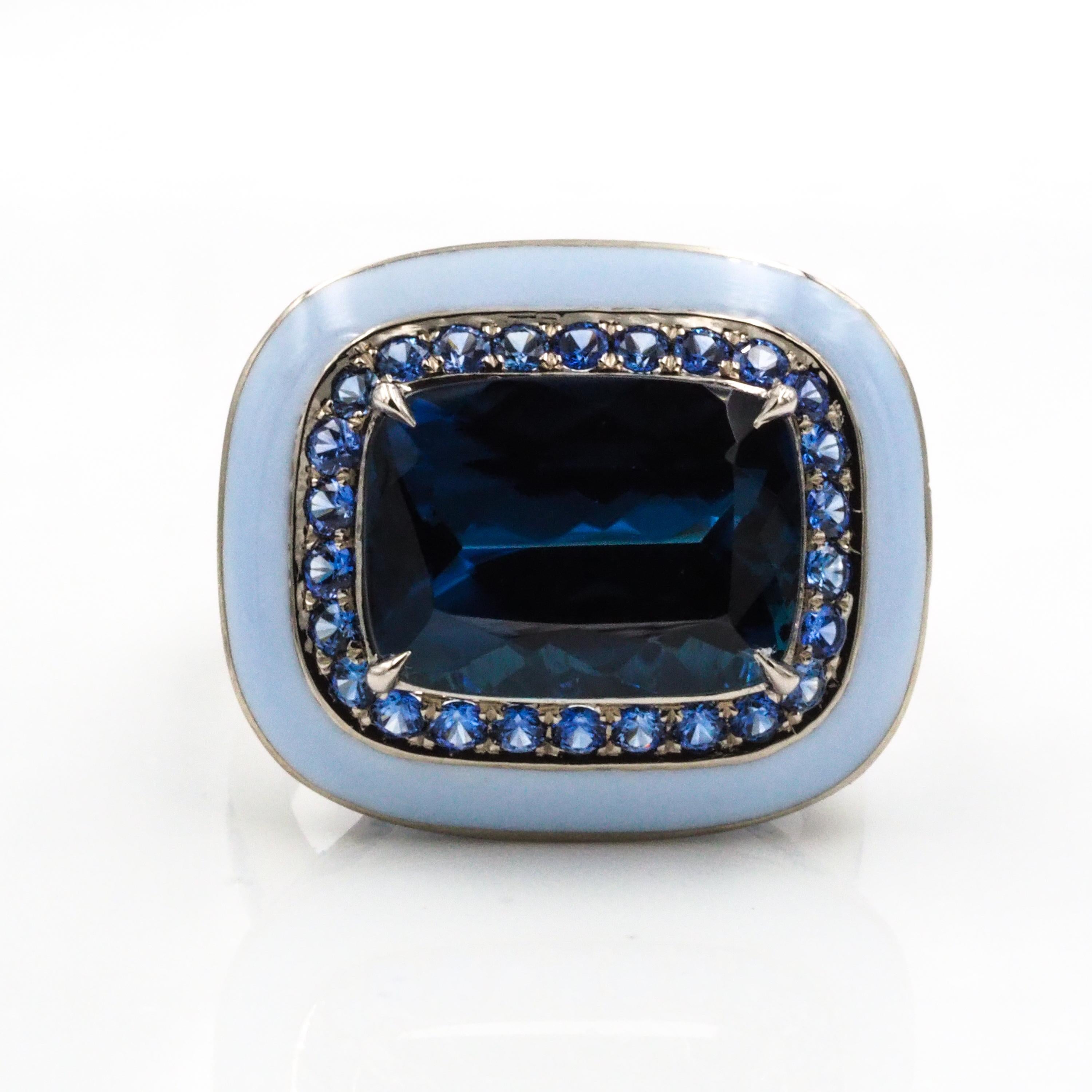 This 18k white gold cocktail ring features an indicolite tourmaline center, surrounded by small blue sapphires. The light blue enamel ceramic enhances the color of the beautiful center stone.

Indicolite Tourmaline: 5.64ct
Sapphires: 1.61ct
Ring