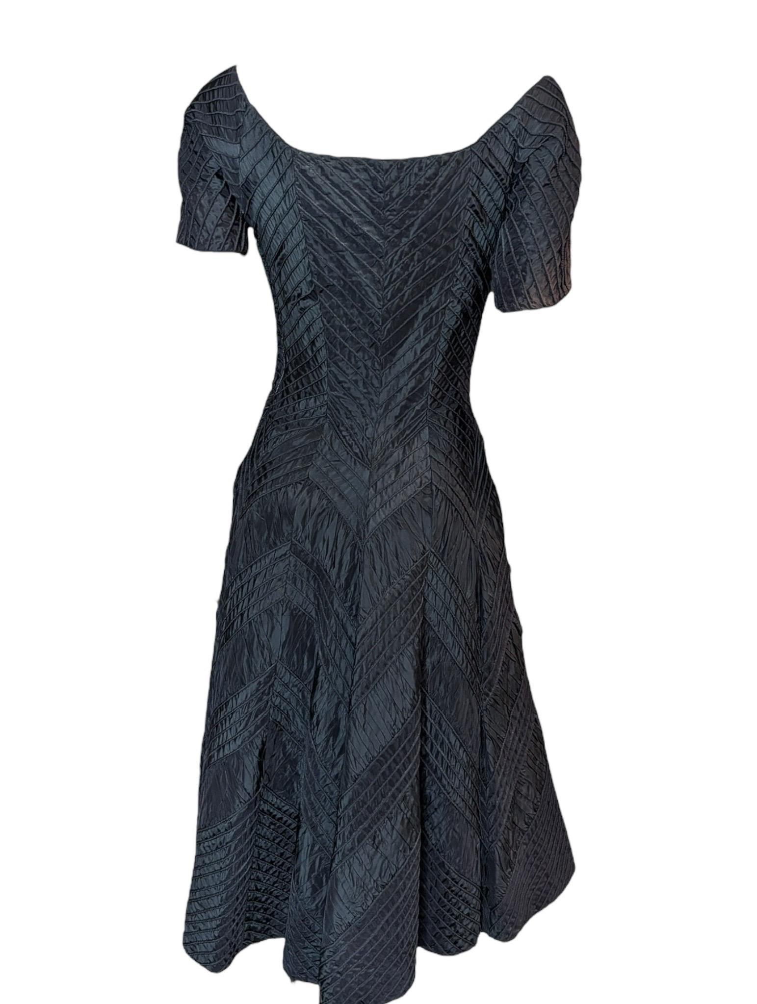 Une superbe robe de cocktail du milieu du siècle de la légendaire créatrice américaine Ceil Chapman, connue pour ses constructions complexes et son drapé caractéristique. Cette robe noire des années 1950 présente une silhouette sculpturale avec un