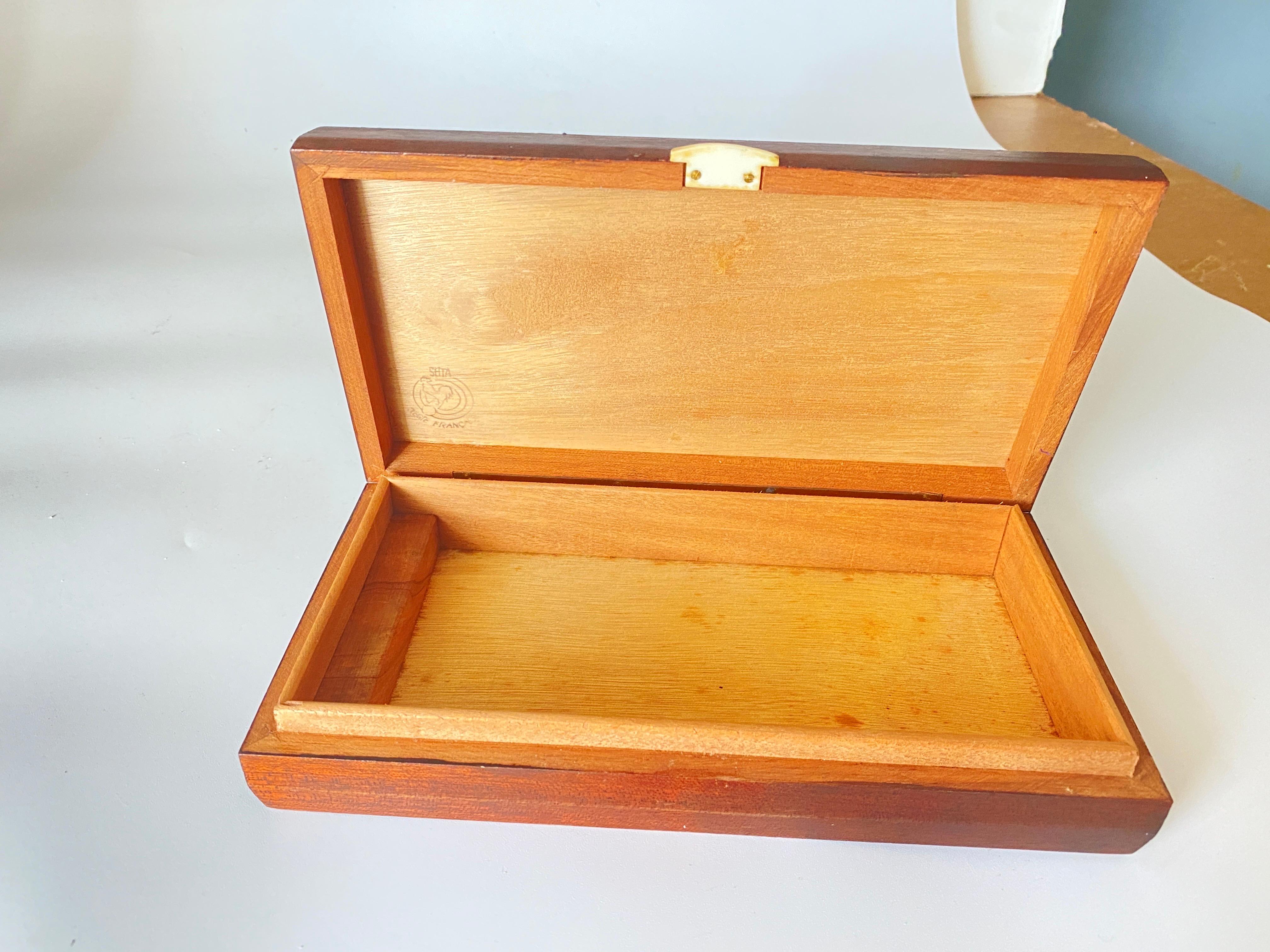 Cette boîte provient de France. Fabriqué en 1940, il s'agit d'un objet art déco. La boîte est en bois.
C'est une boîte à cigares mais elle peut être utilisée comme boîte documentaire, à la maison ou dans un bureau.