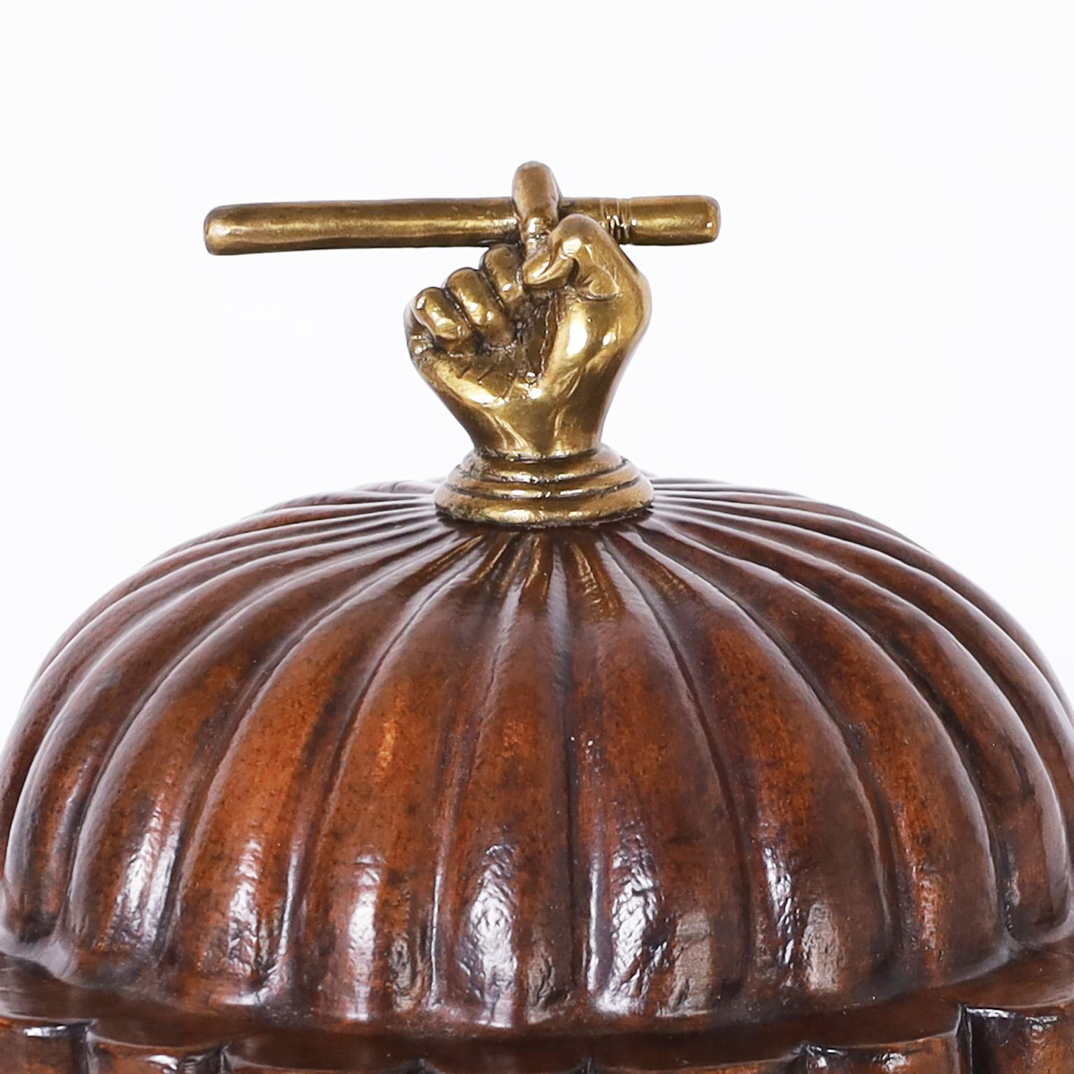 Whimsical midcentury lidded cigar box crafted in cedar and featuring a brass lid handle depicting a cigar in hand, hand painted labels over a tobacco colored finish, and brass tobacco leaf feet.