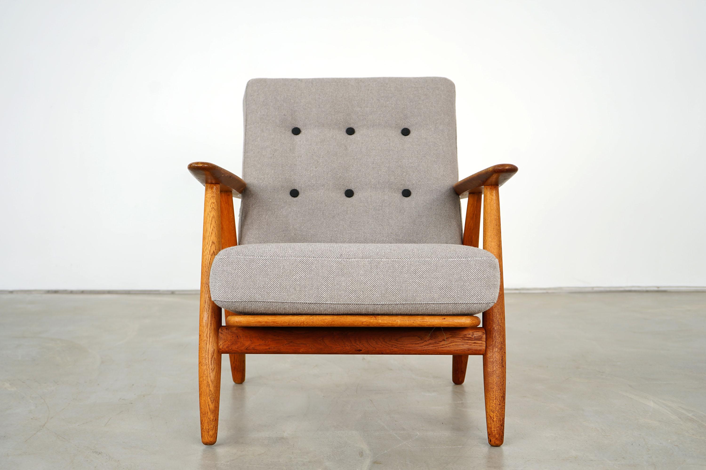 This cigar armchair GE240 was designed by Hans Wegner for the manufacturer GETAMA. The piece is from the 1950s. It is made of oak. The pillows were reupholstered and covered with the high-quality fabric Hallingdal by Kvdrat. The piece of furniture