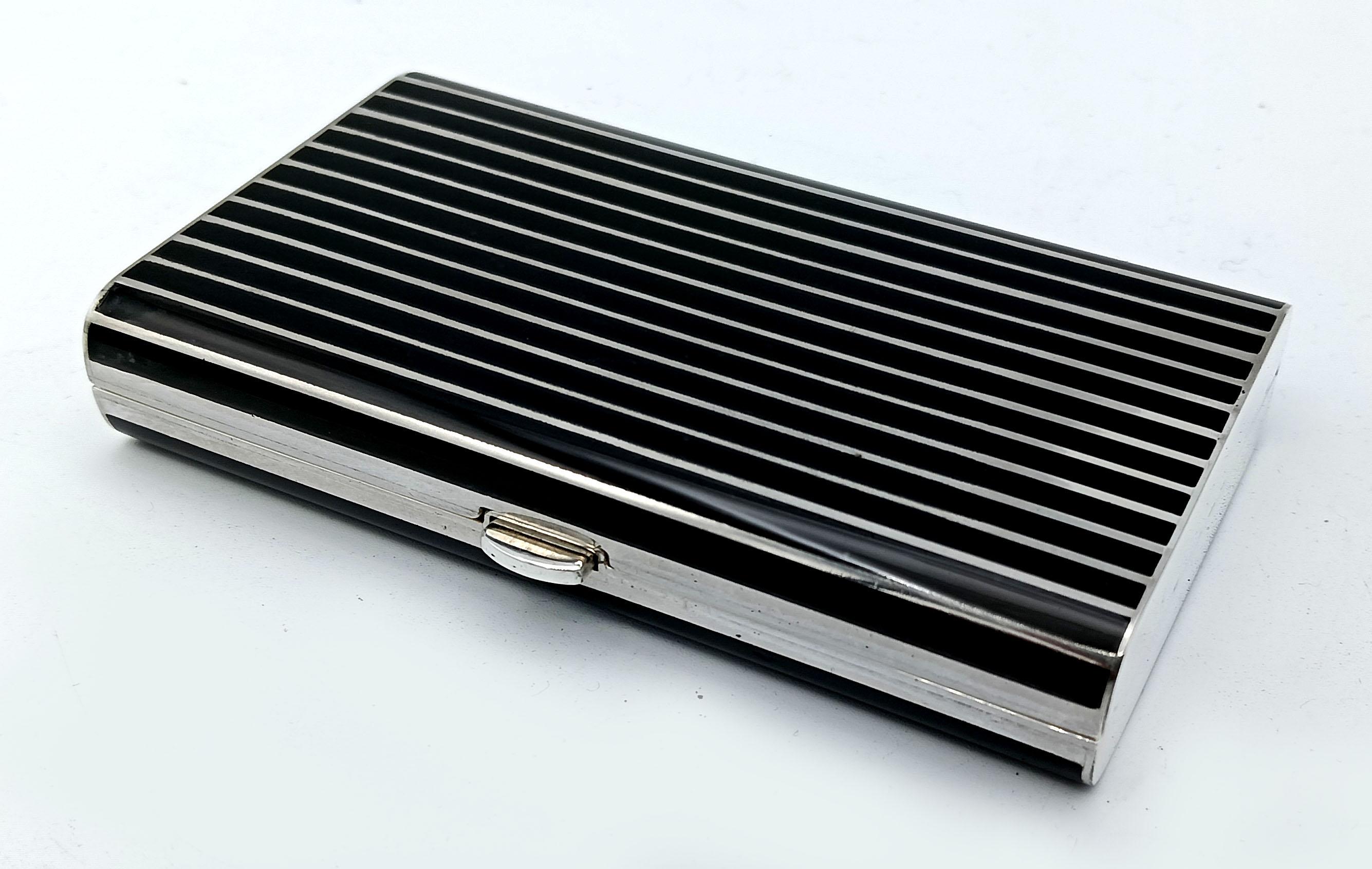  Rectangular pocket cigarette case with long rounded sides in 925/1000 sterling silver with black fire-enamelled stripes. With button and spring opening. Measurements cm. 10.3 x 5.8 x 1.8. Weight gr. 204. Slight chip in the enamel on the bottom,