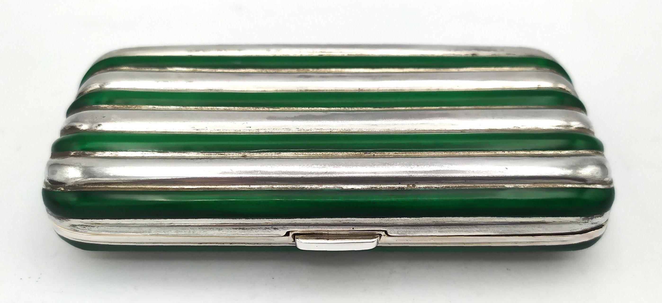 Pitillera de bolsillo rectangular de plata de ley 925/1000 con líneas redondeadas, esmaltada al fuego alternativamente. Con botón de apertura por muelle y bisagra perdida, es decir, semi-invisible. Medidas cm. 5,5 x 10 x 2,3. Peso gr. 172. Inspirado