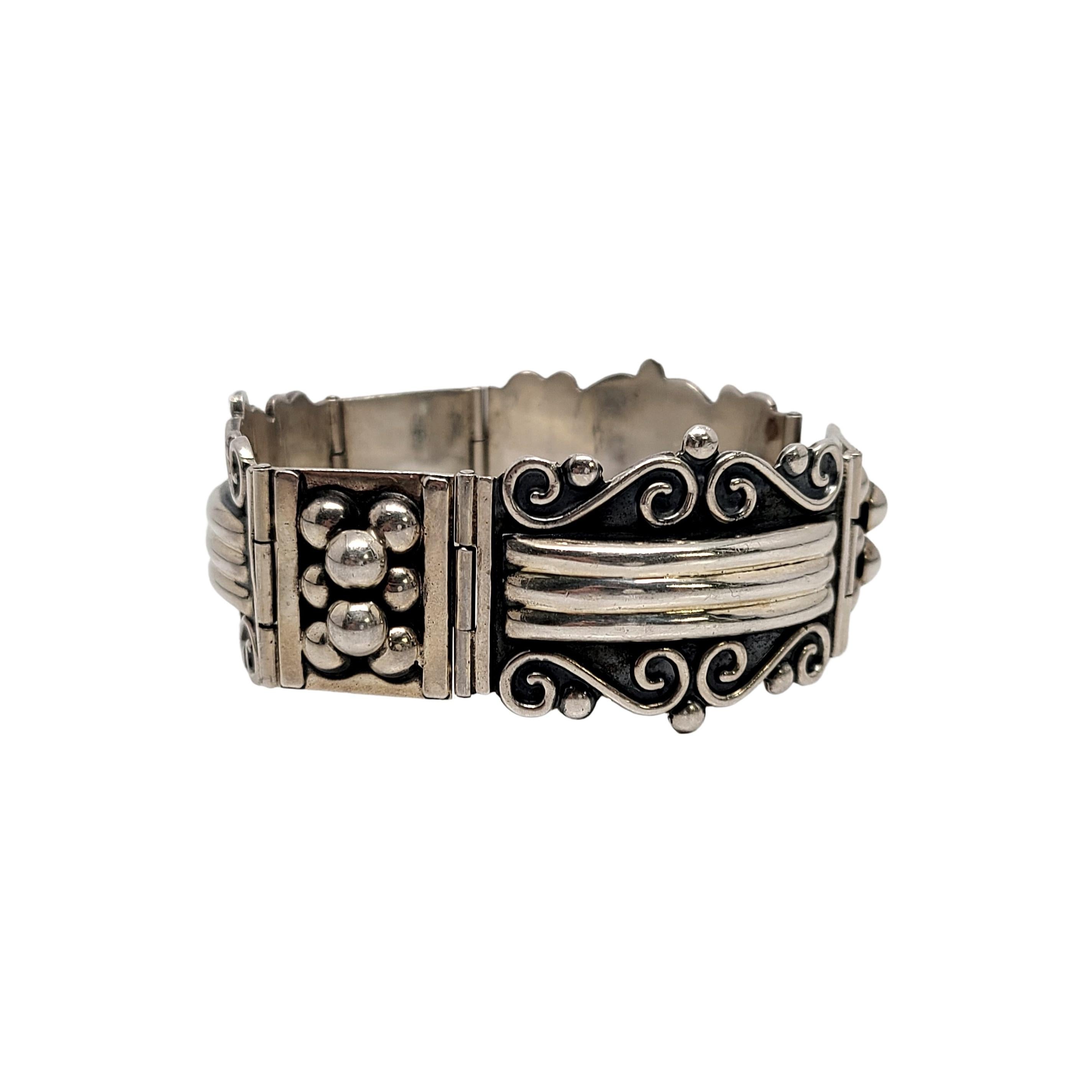 Vintage sterling silver scroll design panel bracelet, signed CII Mexico.

3 rectangular panel scroll design panels alternate with 3 square panels featuring applied round silver beads. Panels are hinged. Slide clasp closure.

Measures approx 7 3/4