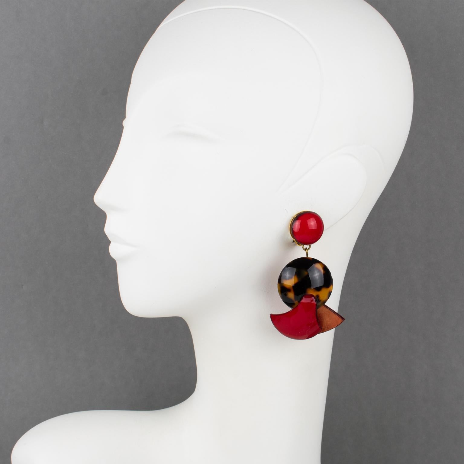 Cilea Paris designs these stunning dimensional dangling resin clip-on earrings. The pieces feature Art Deco revival-inspired artisanal designs with various geometric forms and textural patterns that combine to make a striking statement piece—an