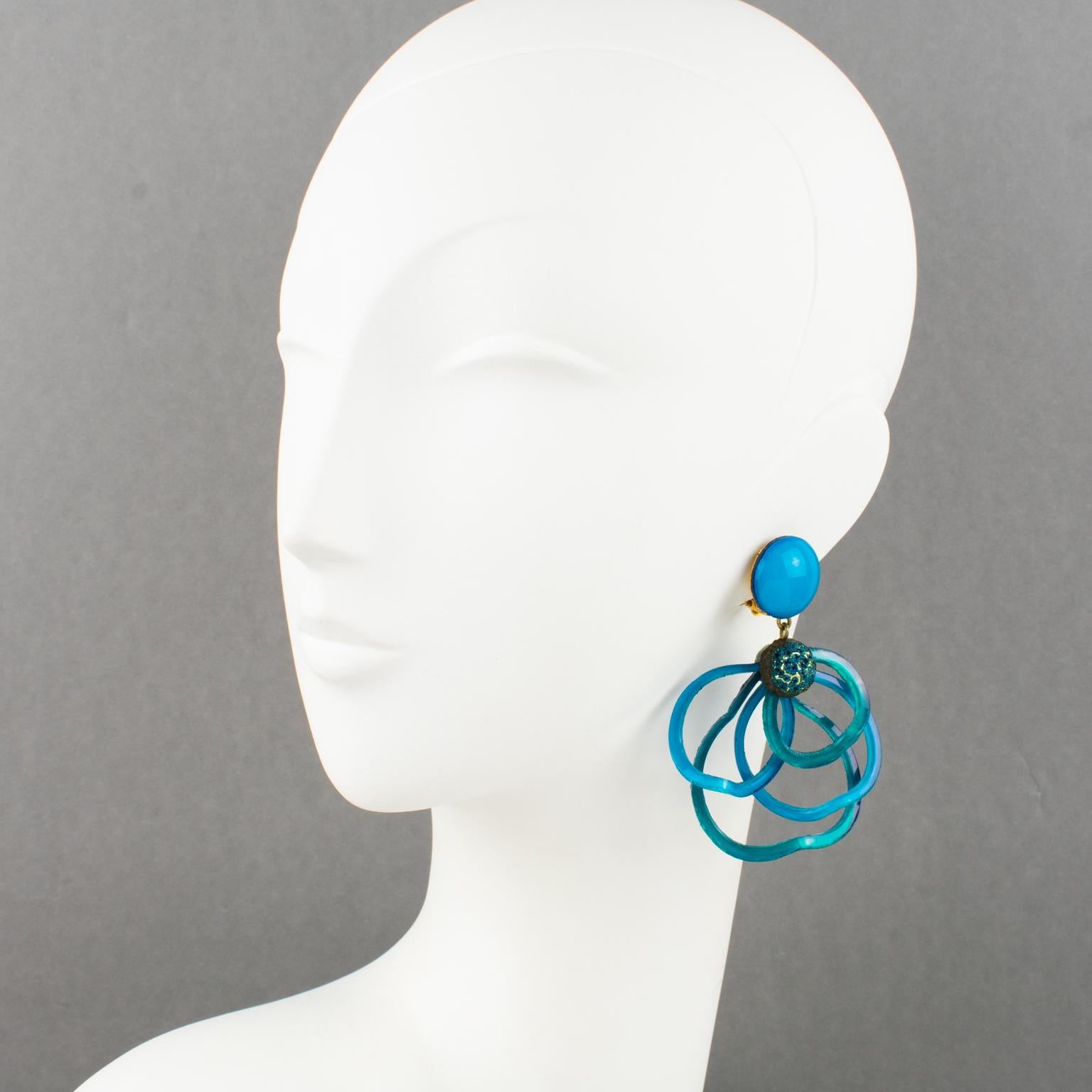 Cilea Paris created these lovely dimensional dangling clip-on earrings. These hand-made artisanal resin earrings feature multi-loop arabesque ribbons textured patterns to build together and form a powerful statement piece. The pieces boast a vivid