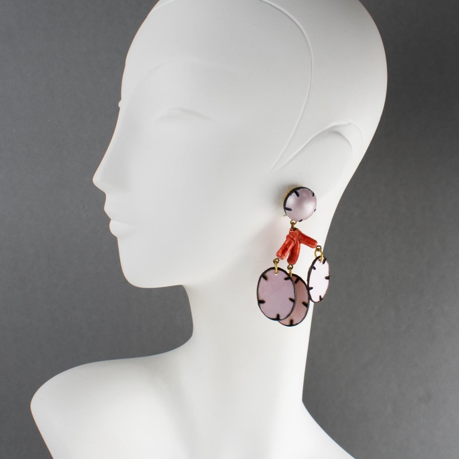 Cilea Paris a conçu ces rares boucles d'oreilles à clip en résine d'inspiration florale. Les pièces légères en résine artisanale sont ornées d'une longue fleur de lunaire au motif texturé. Une palette assortie d'orange corail et de noir contraste
