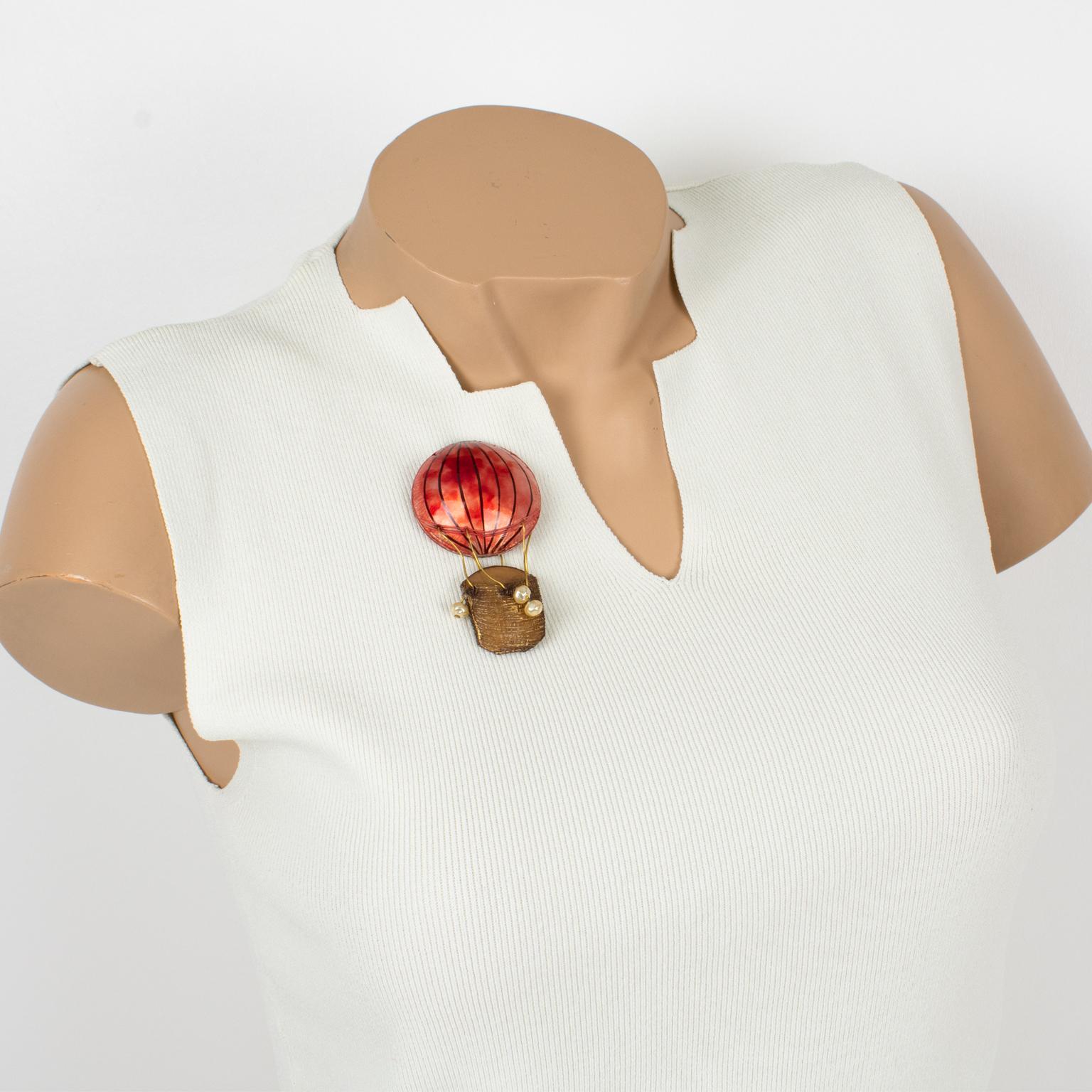 Cilea Paris designed this cute dimensional hot air balloon pin brooch. This fantasy-inspired hand-made artisanal resin piece features a massive air balloon shape with different textured patterns, ornate with pearl-like beads. The pin boasts a pretty