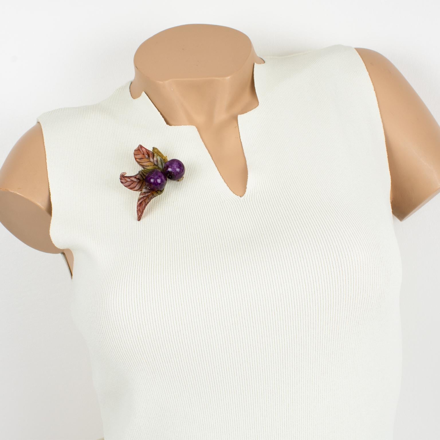 Stunning dimensional floral pin brooch designed by Cilea Paris. This elegant hand-made artisanal resin brooch features colorful berries and leaves in assorted colors of purple, red, green, and rust to form a powerful statement piece. The signature